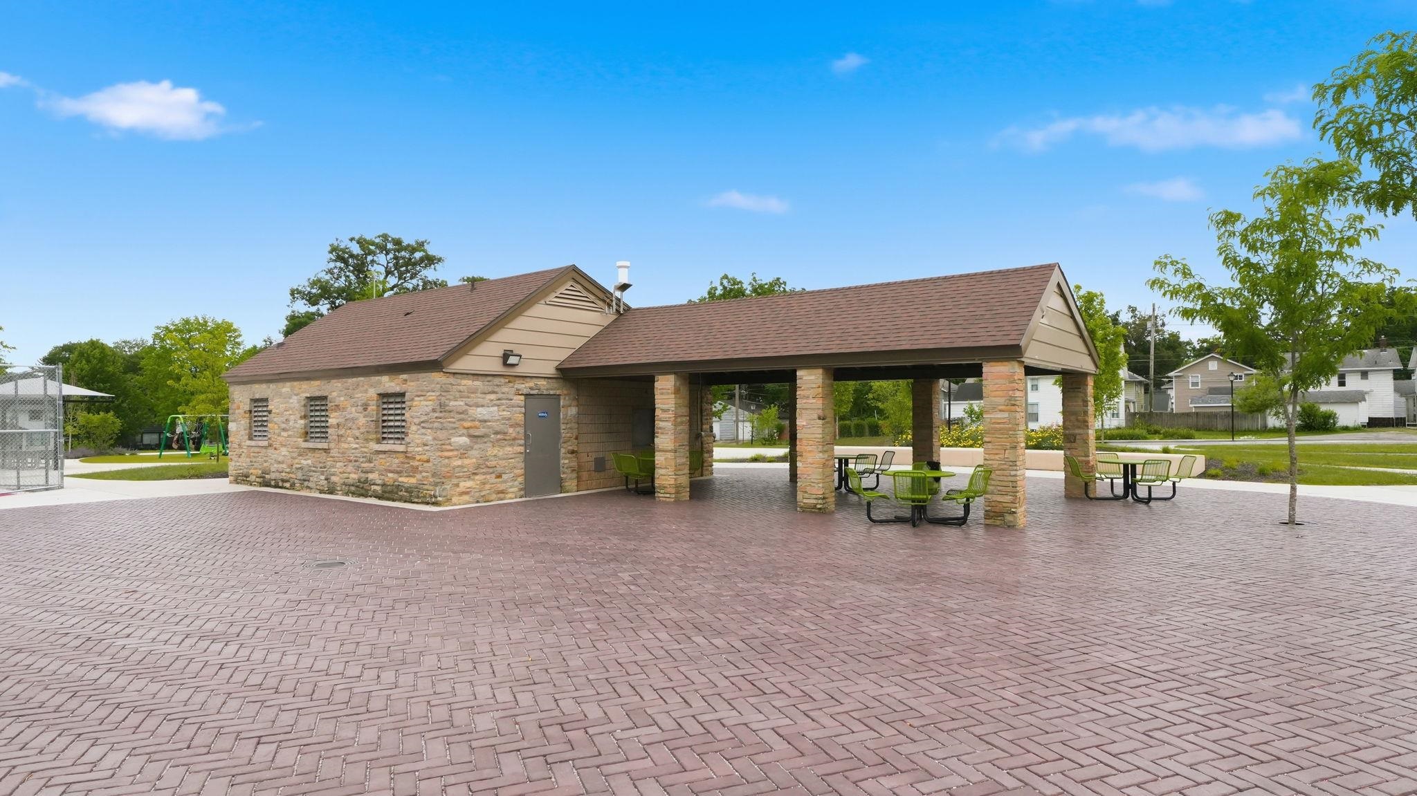 Stone-clad building with a covered outdoor seating area and a herringbone pattern paver surface