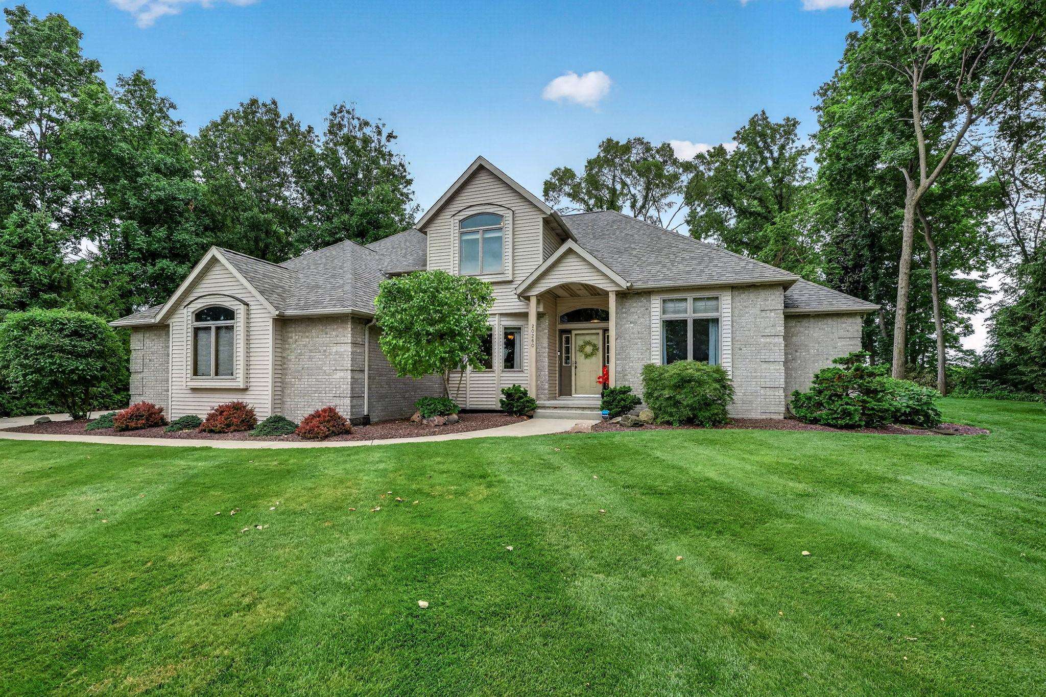 Contemporary residence featuring a brick facade with light-colored siding accents, a prominent front entry with a transom window, and a gabled roofline