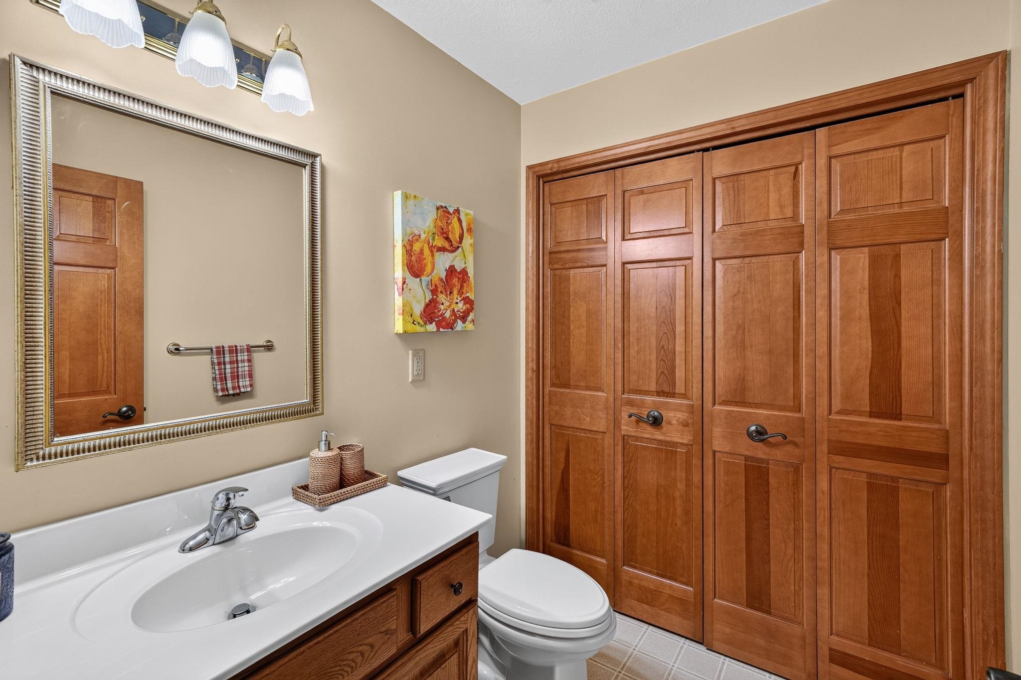 Bathroom featuring a vanity with an integrated sink, polished chrome faucet, wood-finish cabinetry, and a framed mirror with overhead lighting