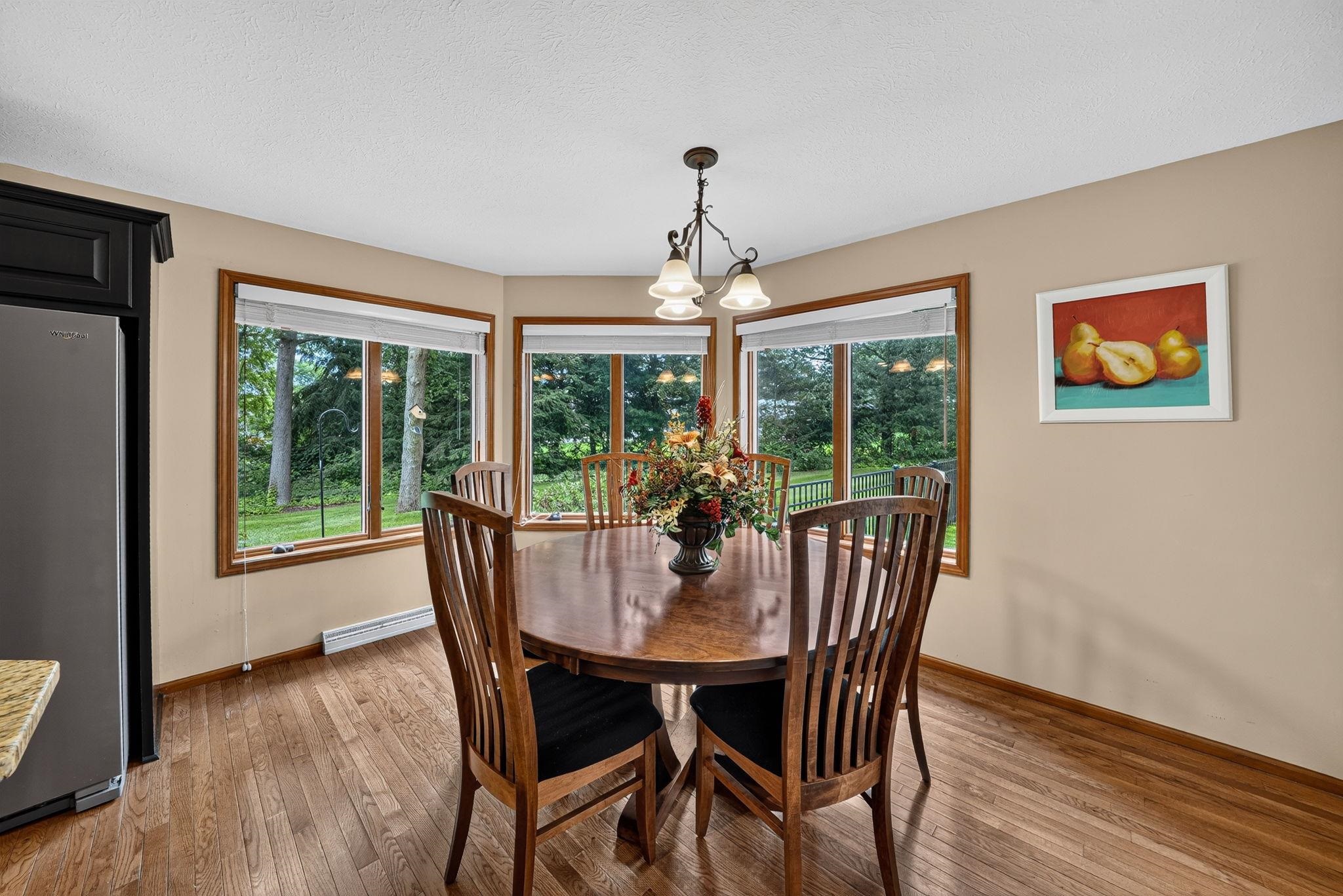 Dining area featuring wood-finish flooring, a bay window with wood trim, and a ceiling-mounted light fixture