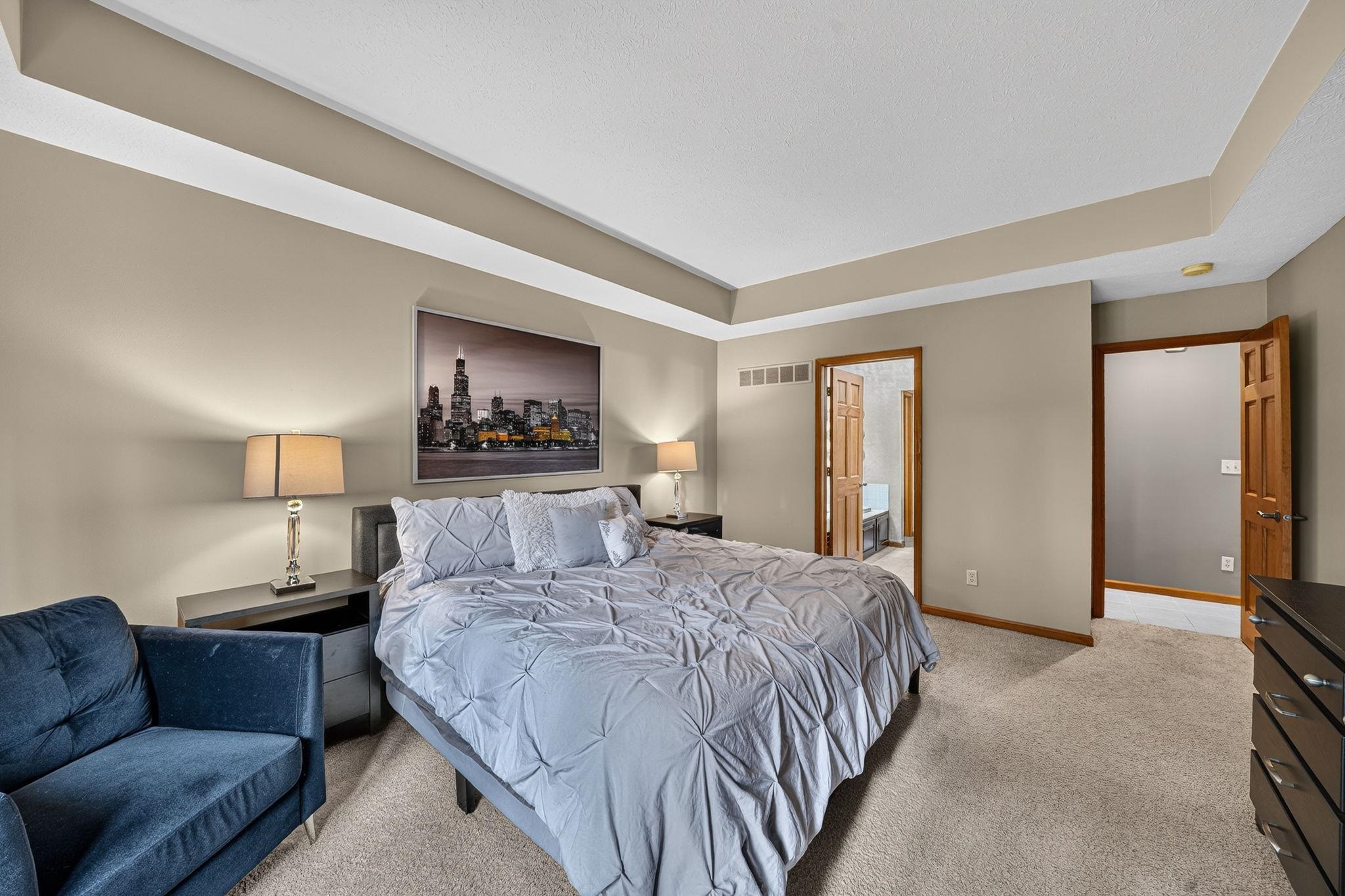 Carpeted room featuring a tray ceiling, neutral wall paint, and multiple doorways with wood-finish trim