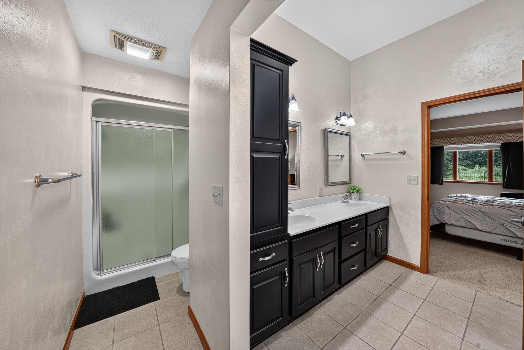 Bathroom featuring a double vanity with dark cabinetry, integrated sinks, and chrome hardware