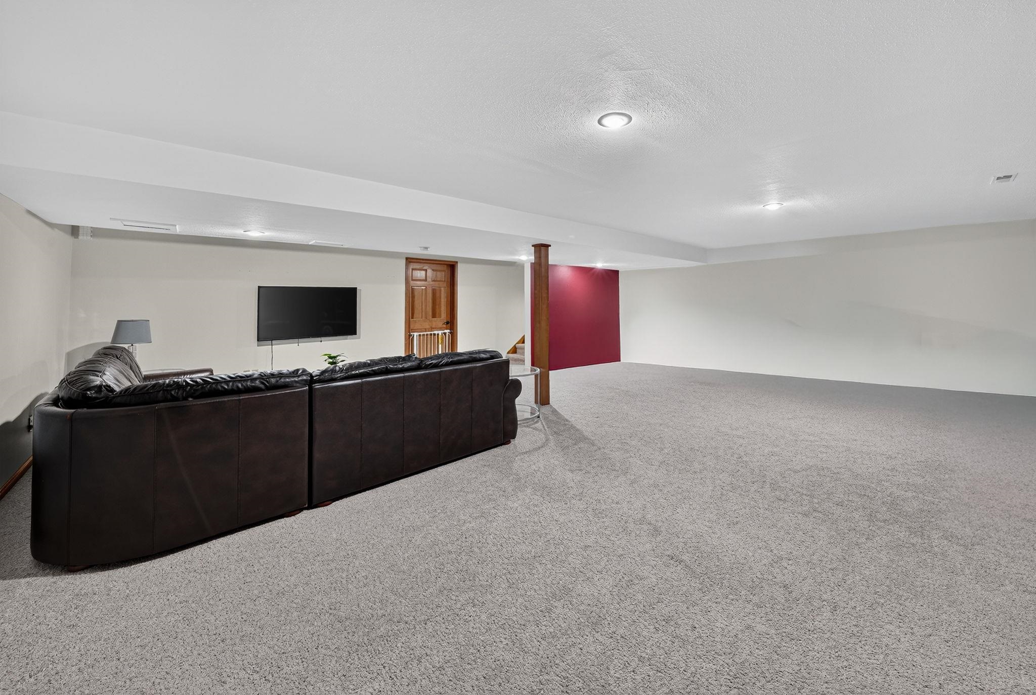 Expansive carpeted room with recessed lighting and a contrasting accent wall