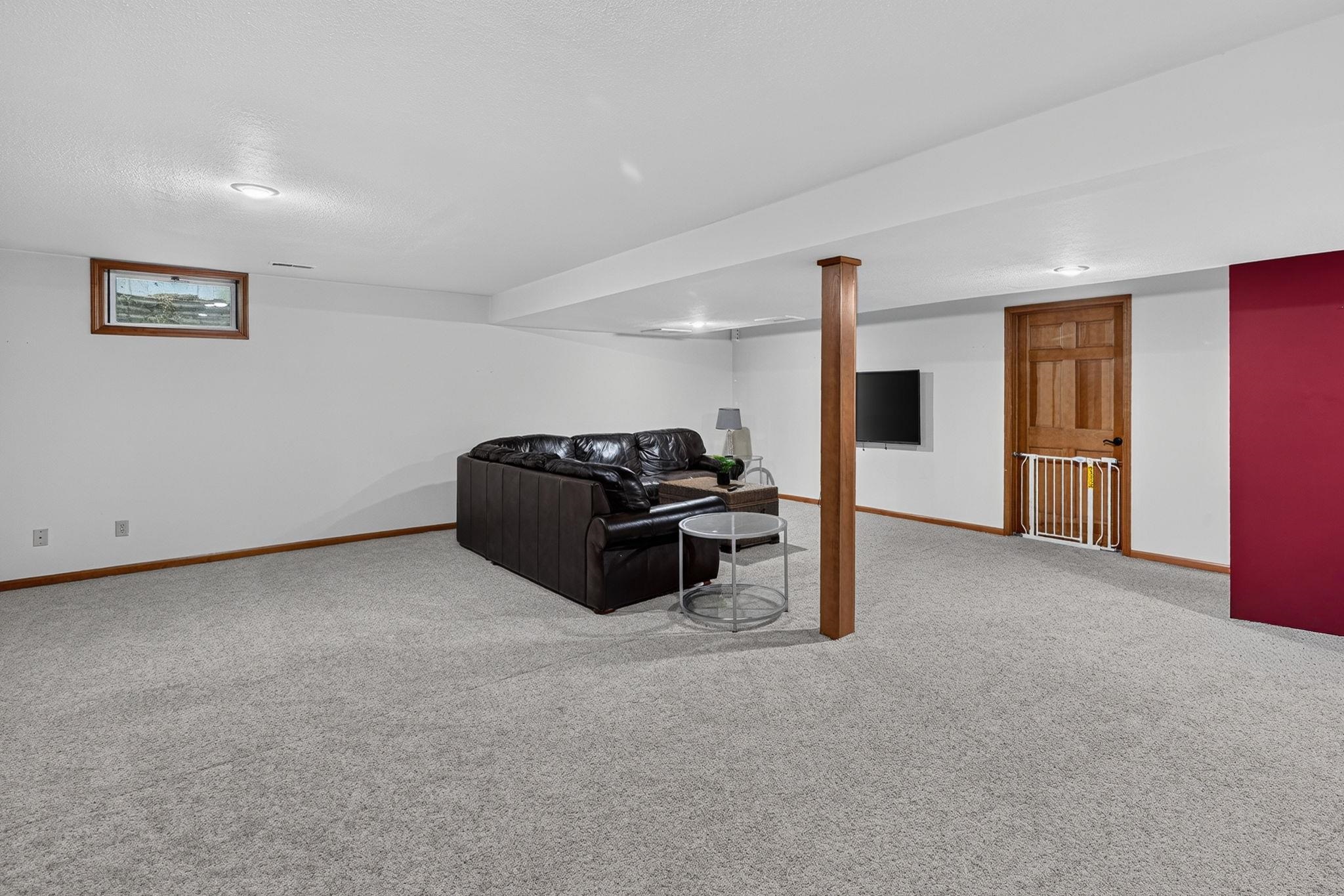 Spacious carpeted room featuring recessed lighting, a wood-trimmed window, and a wood support column