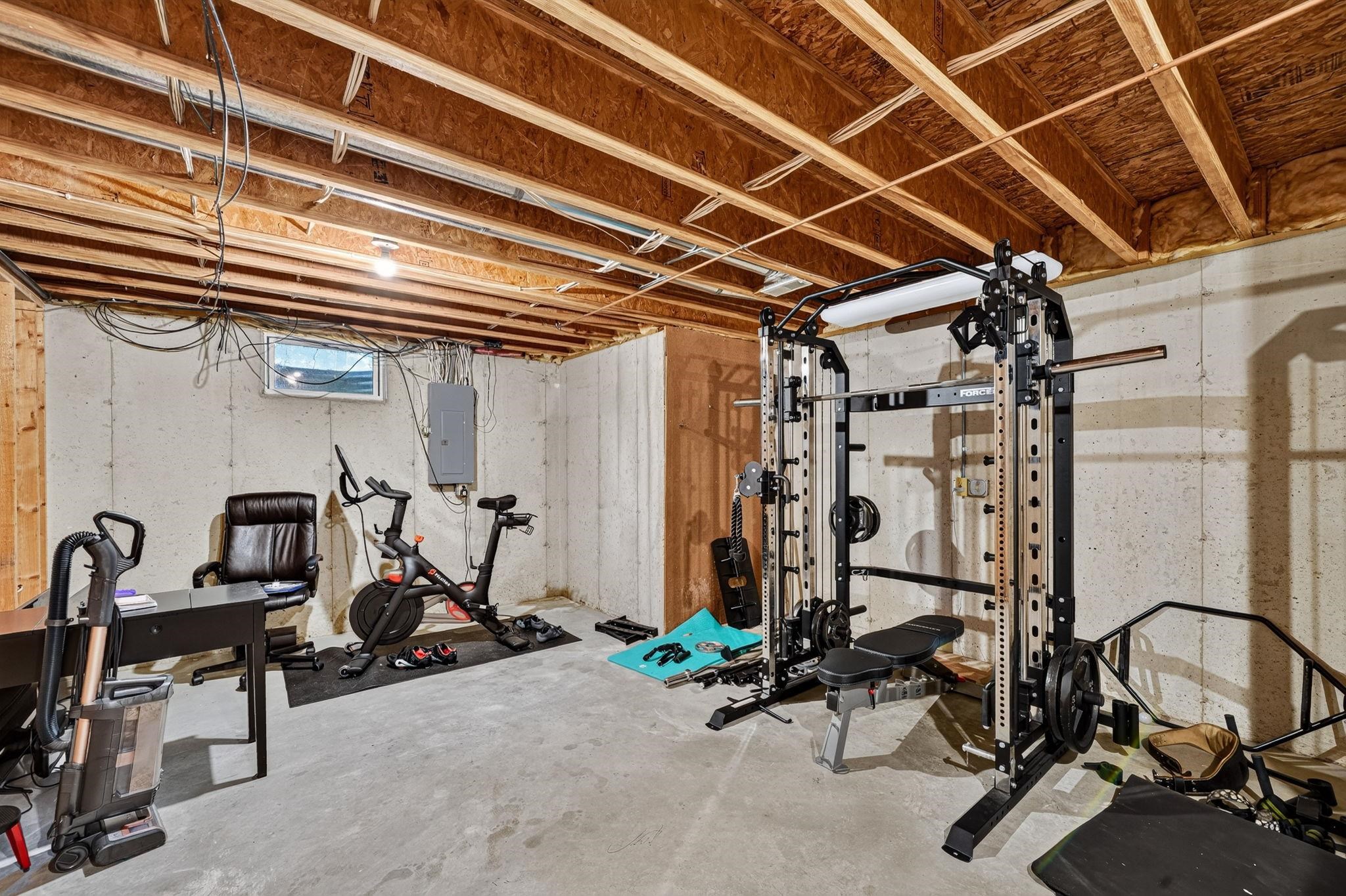 Unfinished lower level featuring exposed wood joists and concrete flooring