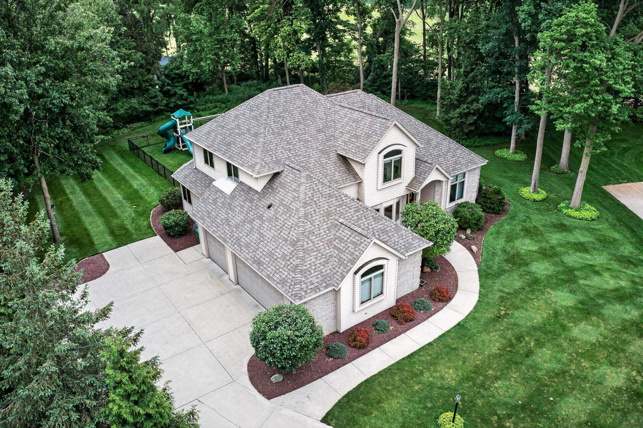 Spacious residence featuring a multi-car driveway, a stone-accented exterior, and a shingle roof