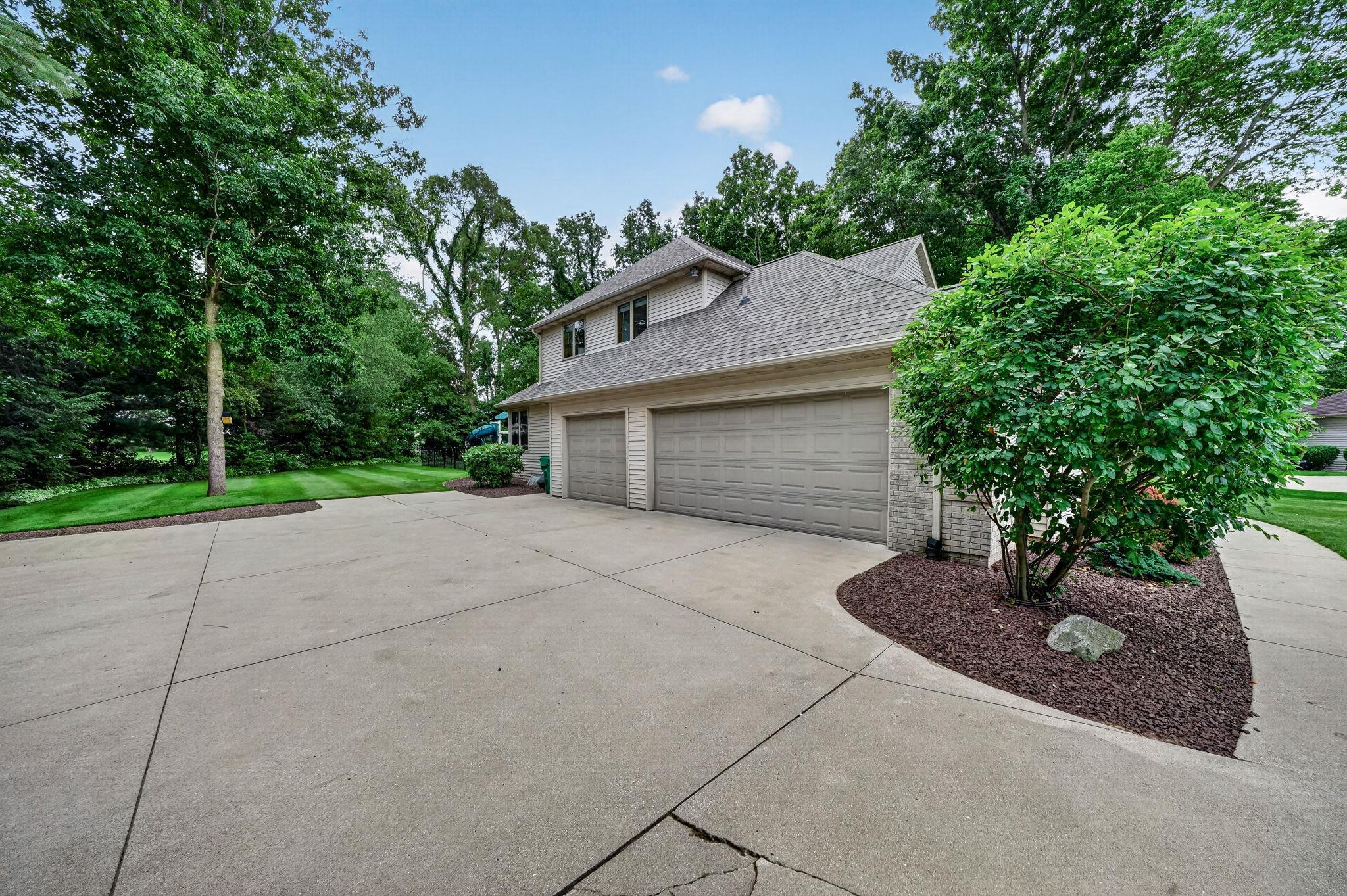 Spacious concrete driveway leading to a three-car garage