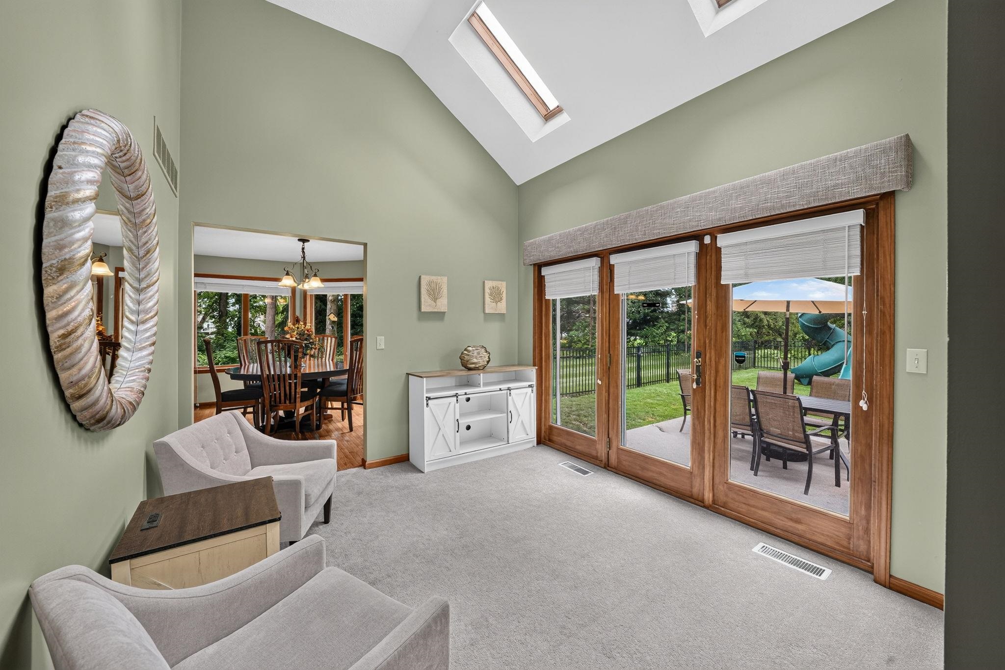 Vaulted ceiling with skylights above a living space featuring light grey carpeting