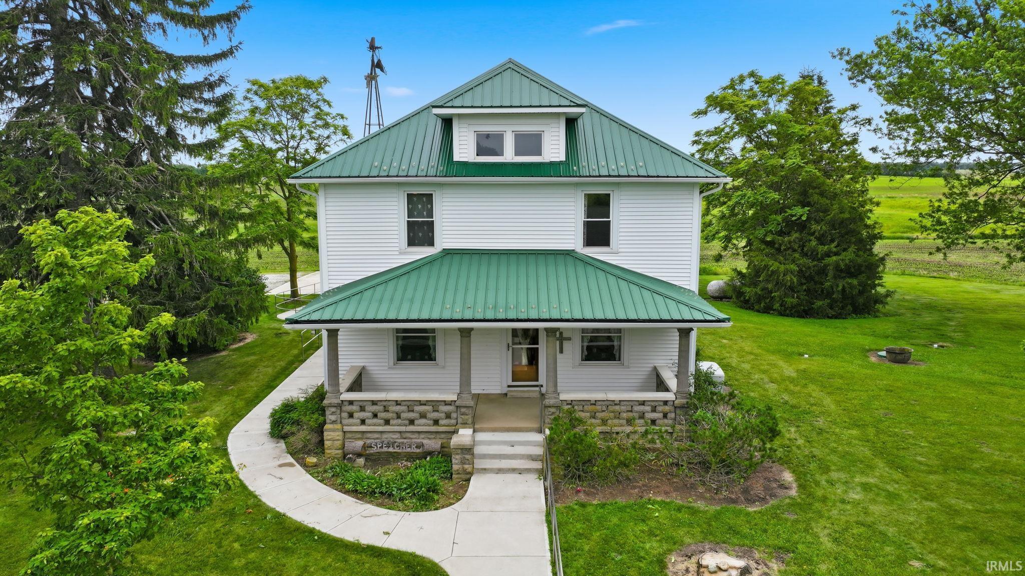 Traditional residence featuring a white siding exterior and green metal roofing