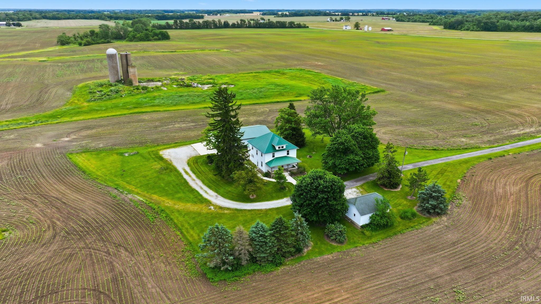 Aerial perspective showcasing a sprawling property with a white residence featuring a green roof