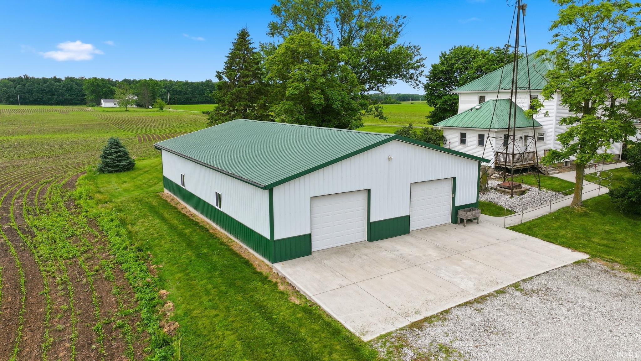 Pole barn with a green metal roof, white siding, and green trim