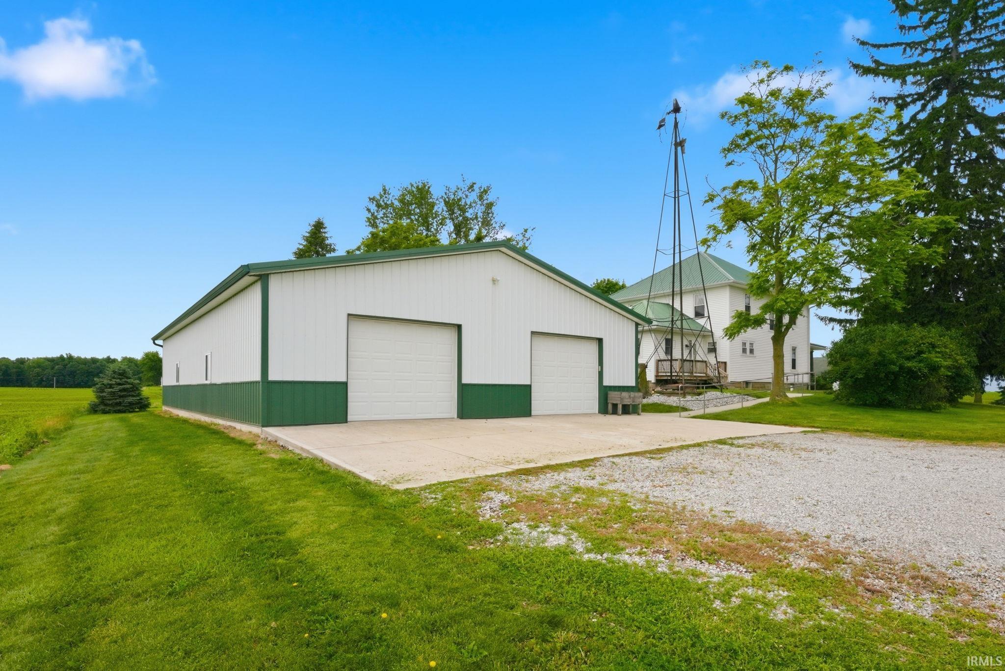 Pole barn featuring two garage doors, concrete pad, and white and green metal siding