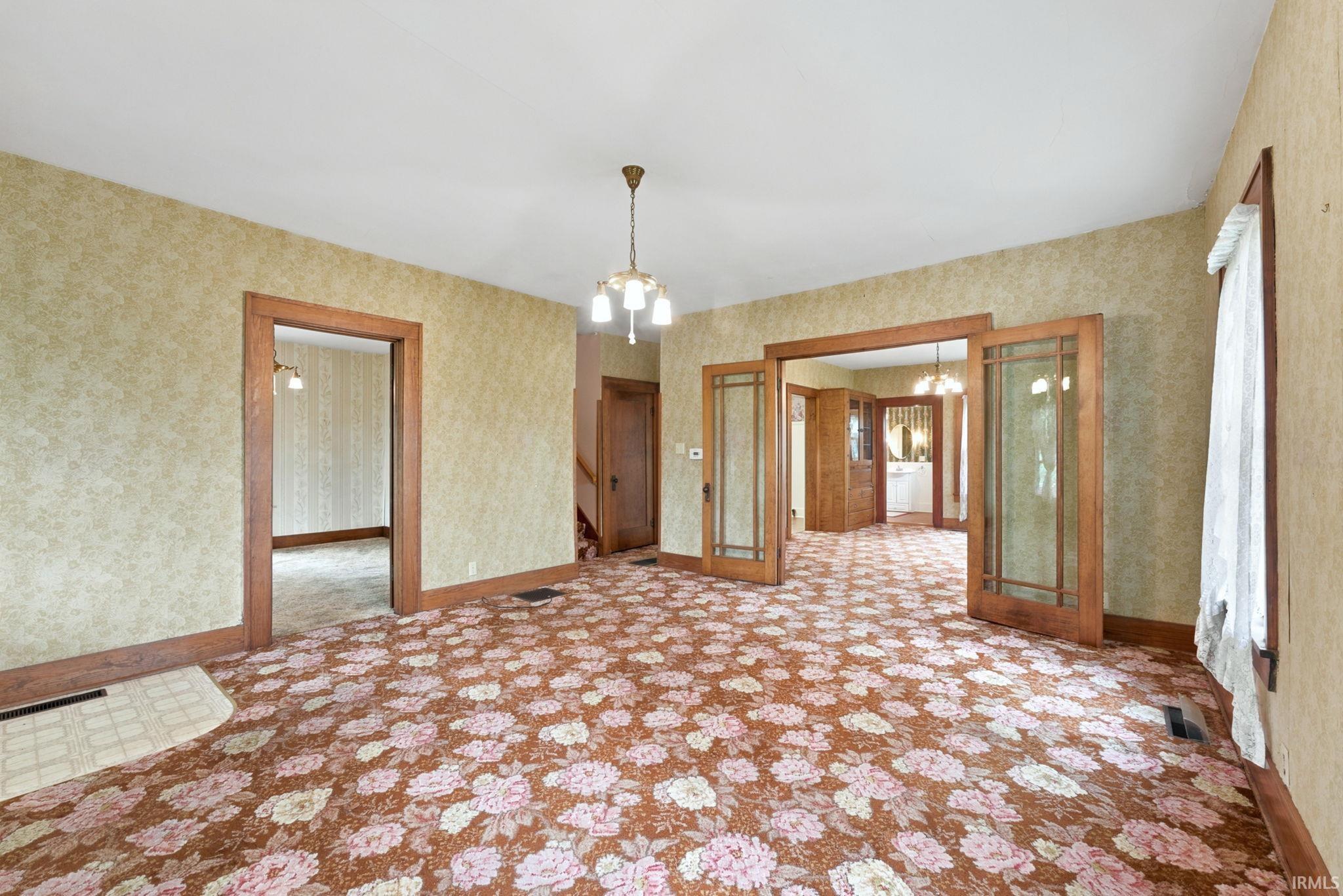 Interior room featuring a ceiling-mounted chandelier, wood trim, and a patterned carpet