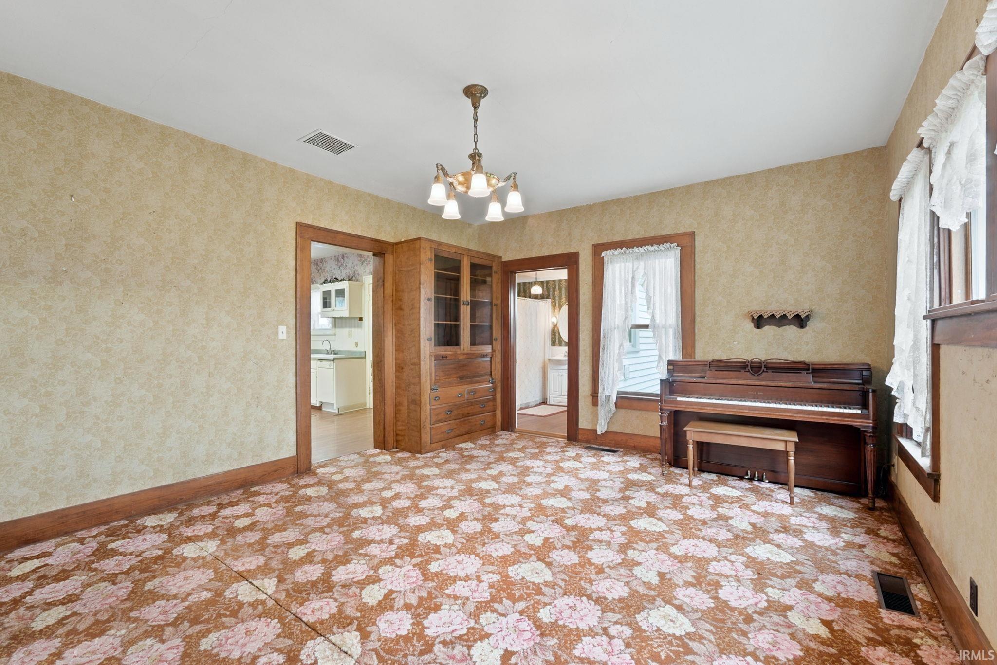 Spacious room with floral-patterned carpeting, wallpapered walls, and dark wood trim