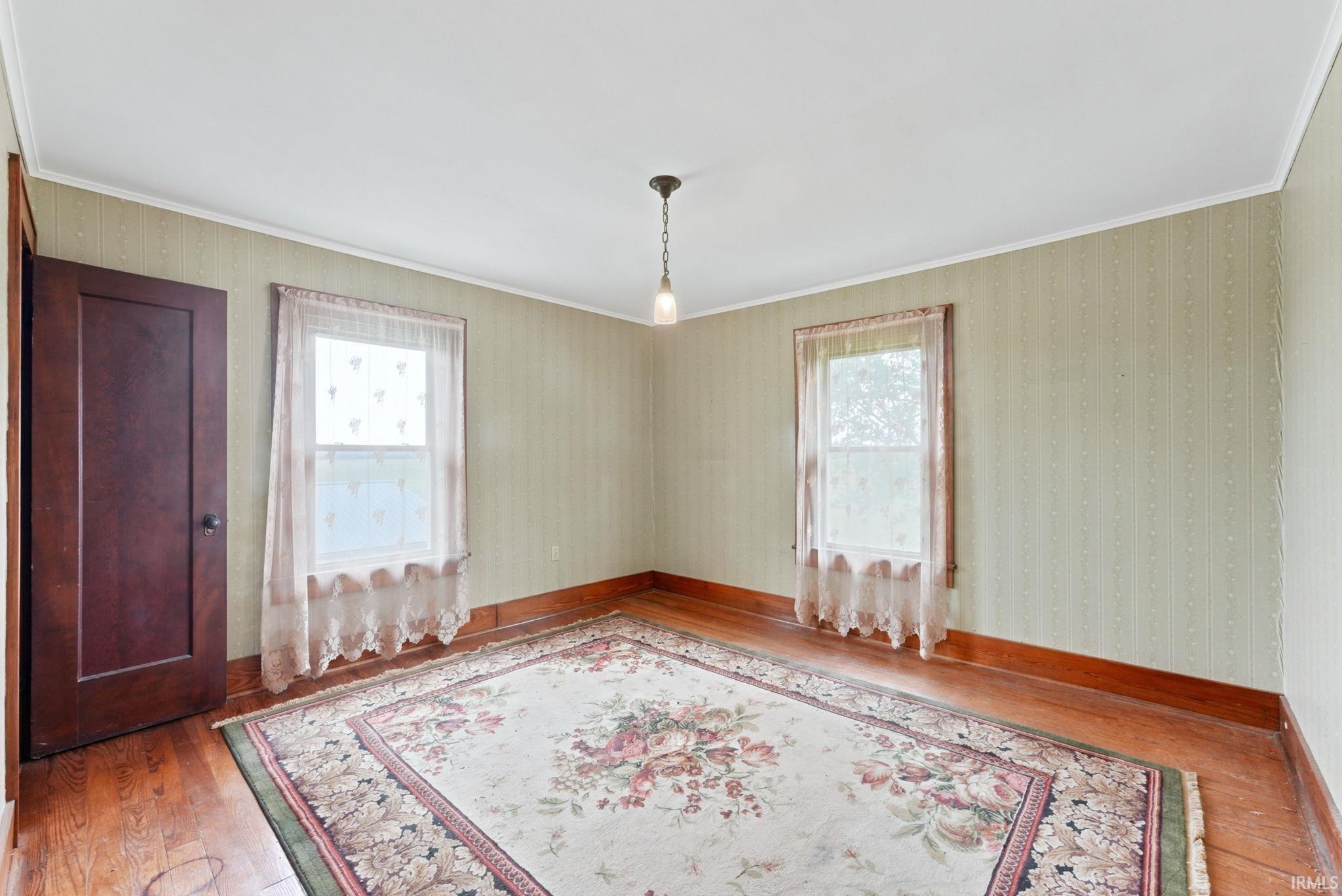 Room featuring wood-finish flooring, a pendant light fixture, and two windows