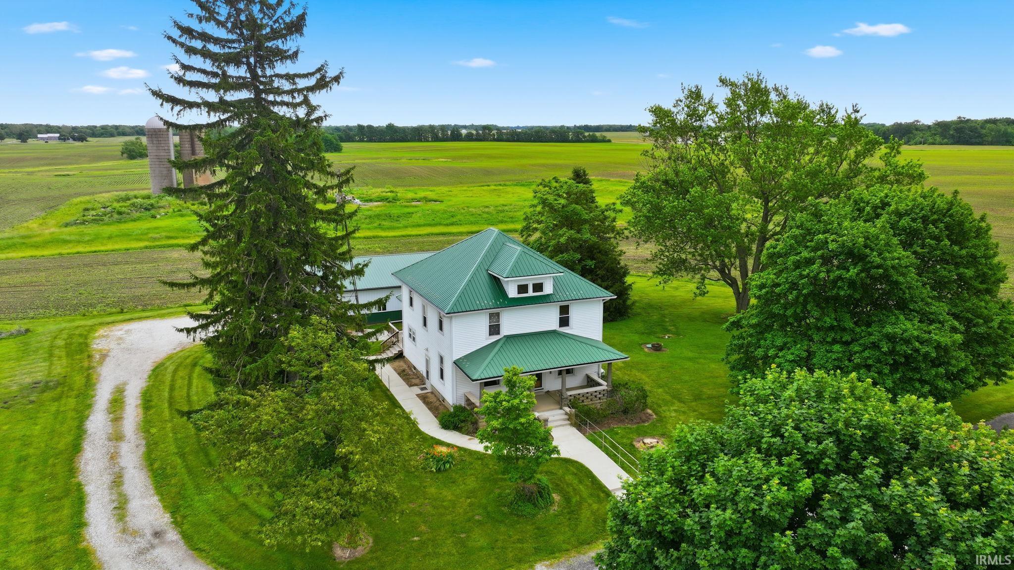 White two-story residence featuring a green metal roof and an inviting covered porch