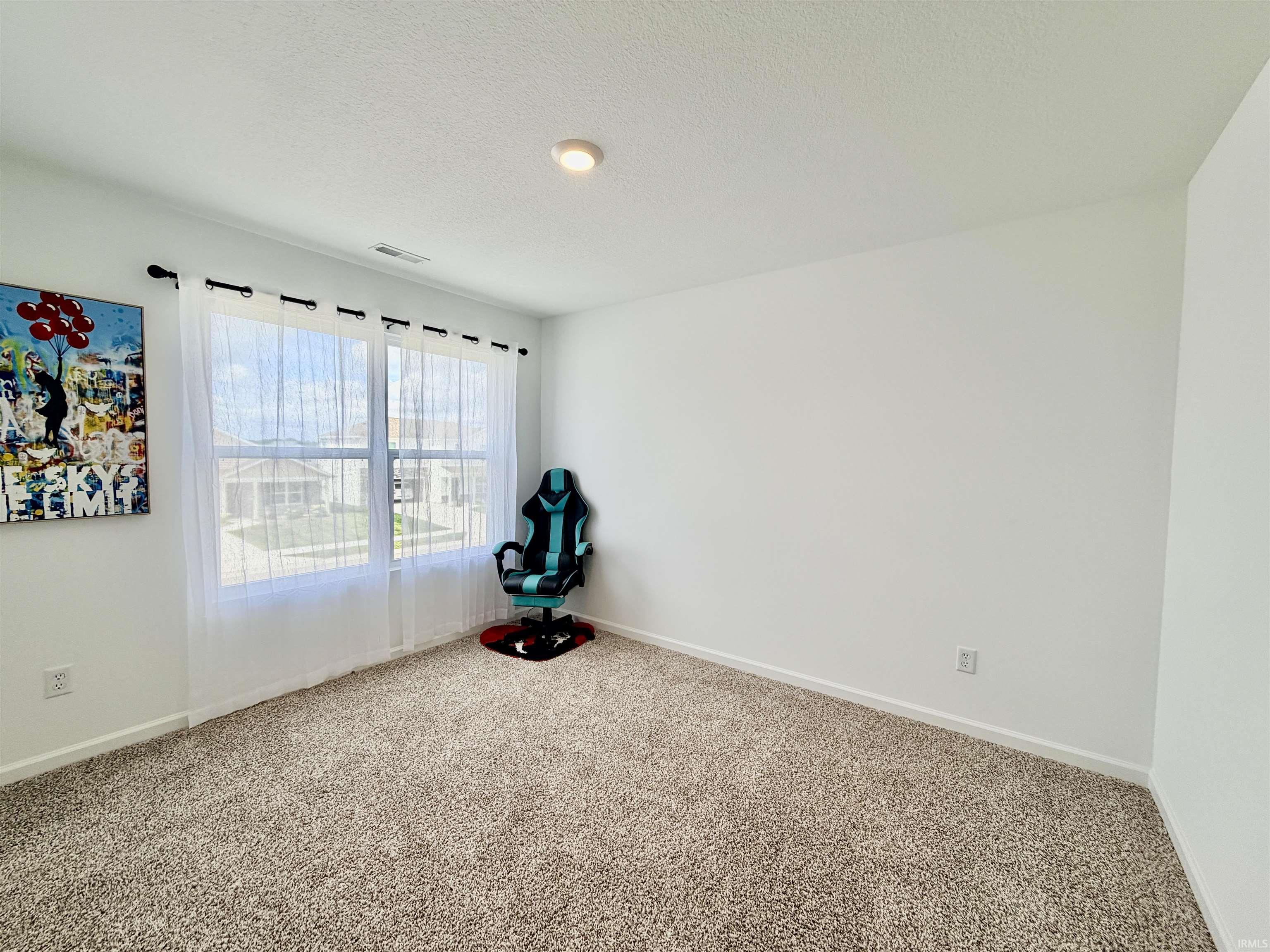Bright room with a large window, neutral carpet flooring, white walls, recessed lighting, and white baseboards