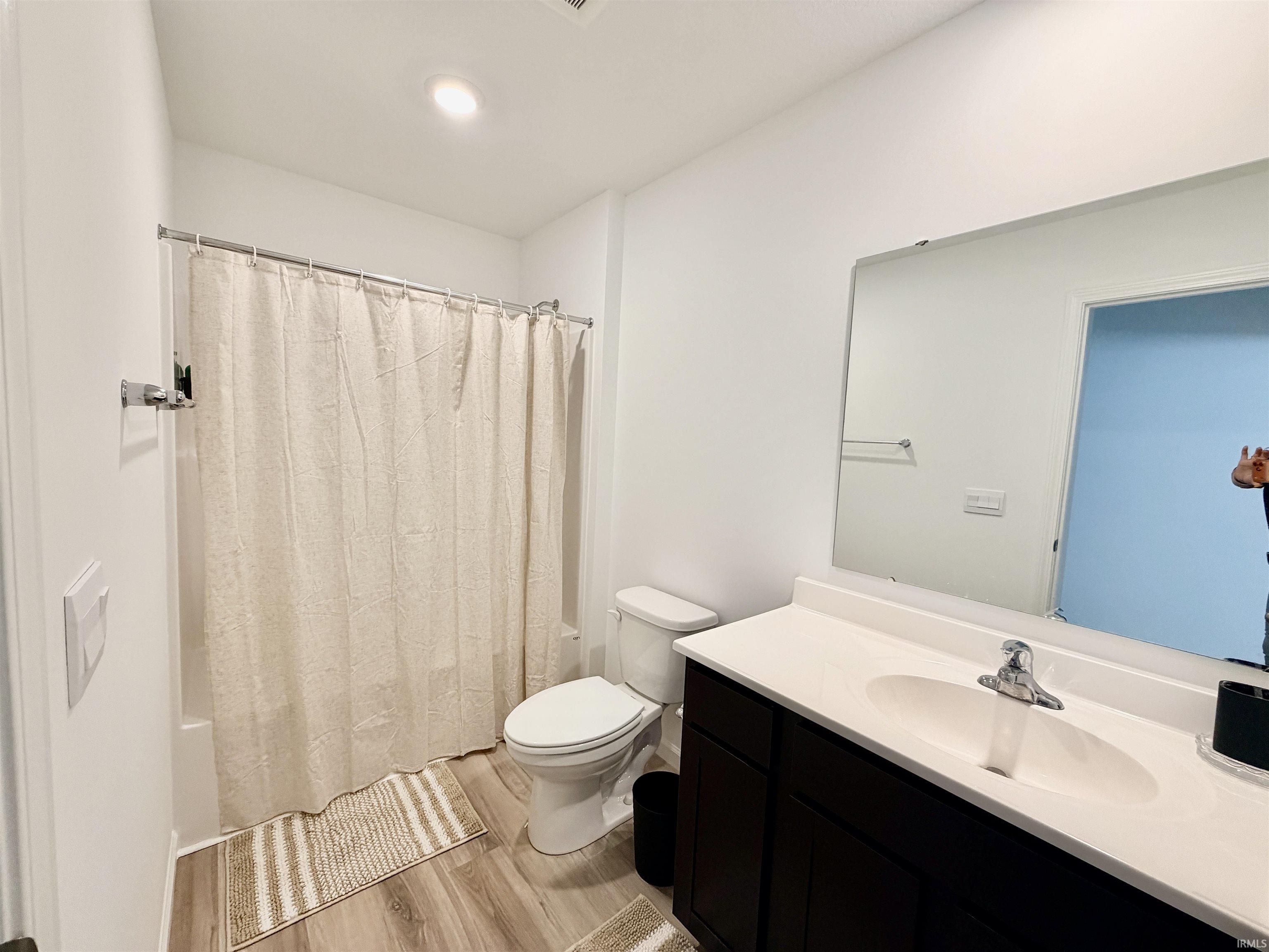 Full bathroom featuring a single vanity with a white countertop and dark wood-finish cabinetry, a chrome faucet, and a large wall-mounted mirror
