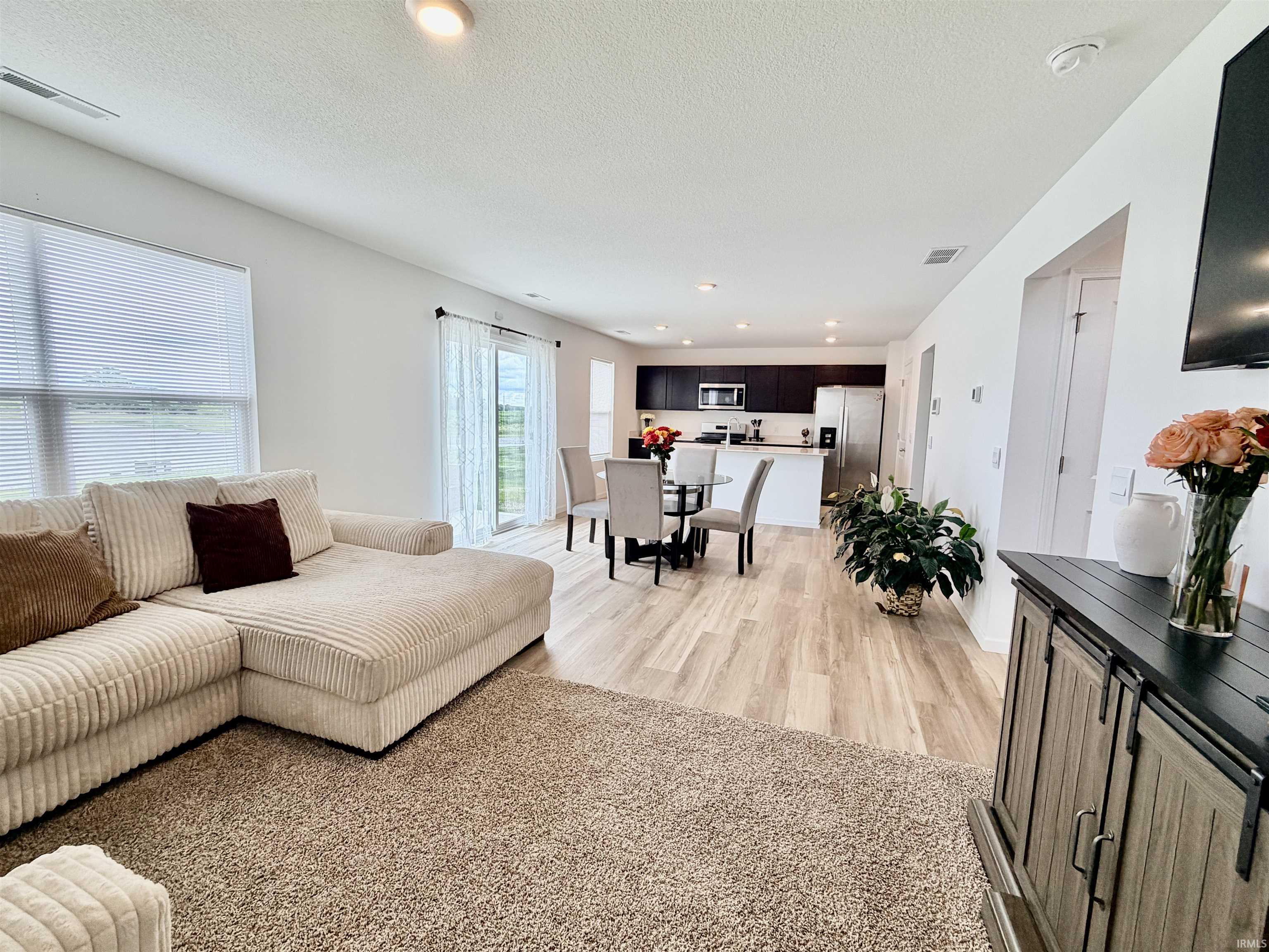 Open-concept living space featuring wood-finish flooring, recessed lighting, and a sliding glass door leading to the exterior