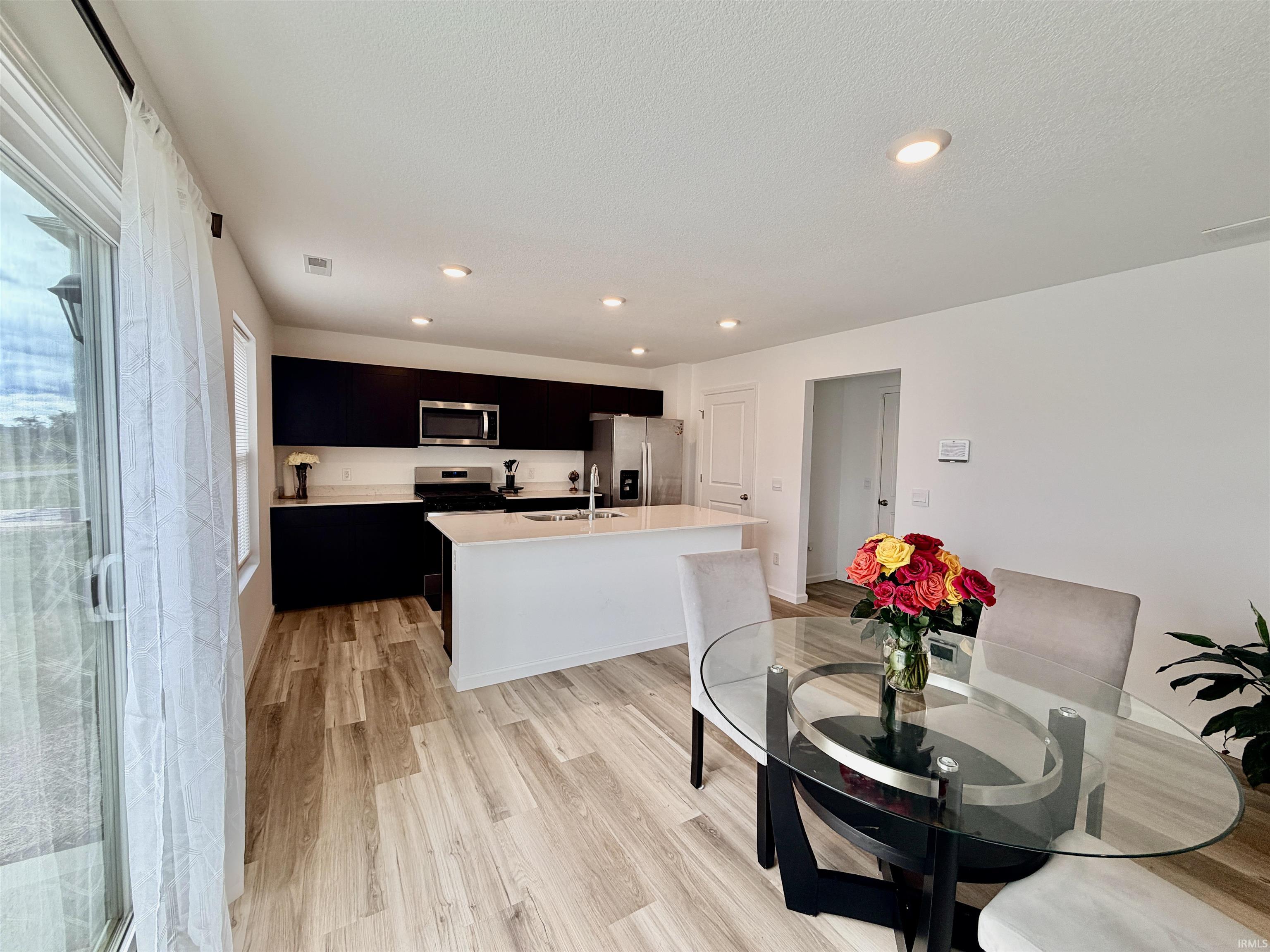 Contemporary kitchen with dark cabinetry, light countertops, and stainless steel appliances