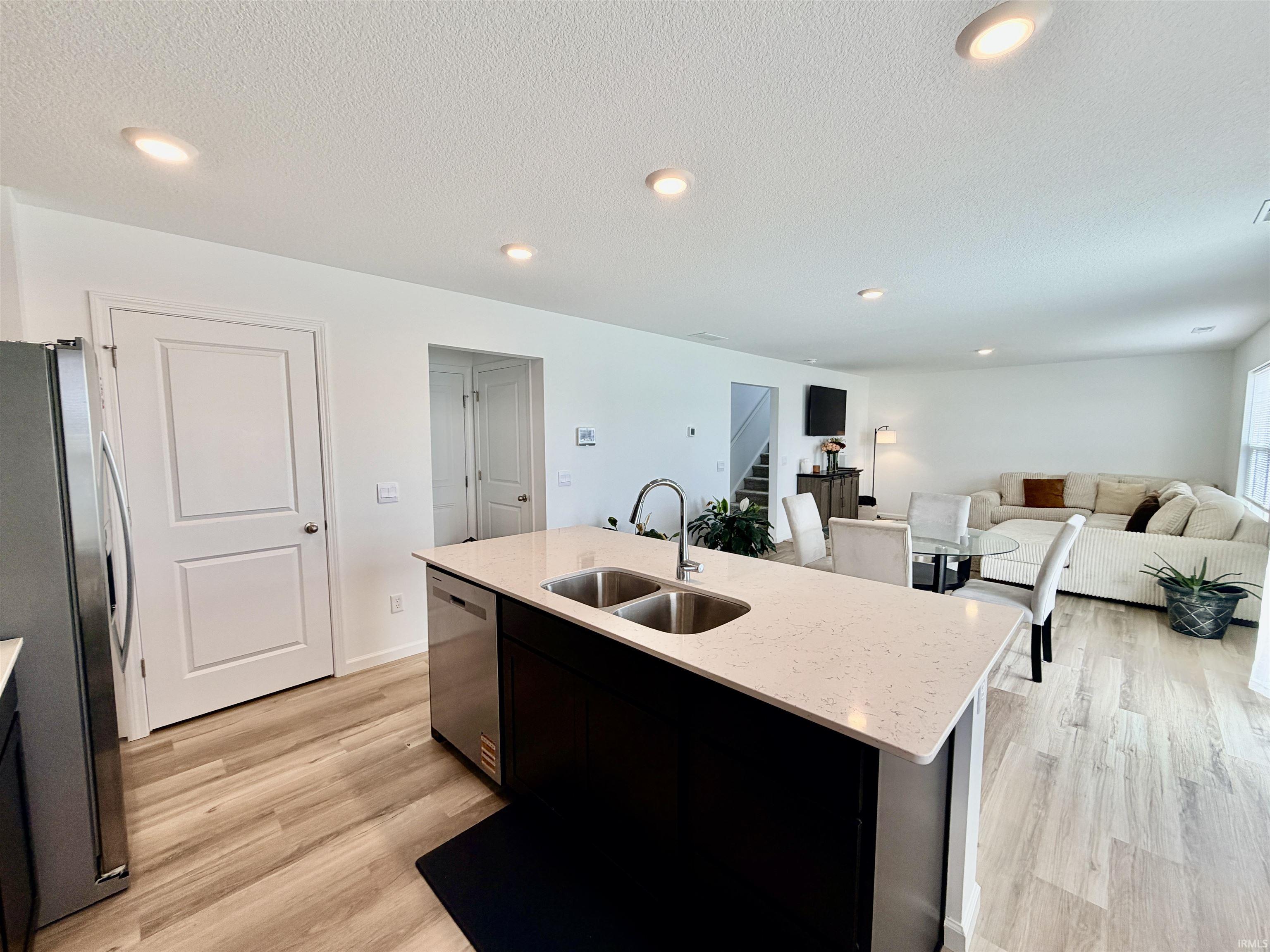 Kitchen island featuring a double-basin stainless steel sink, gooseneck faucet, and light-toned solid surface countertop