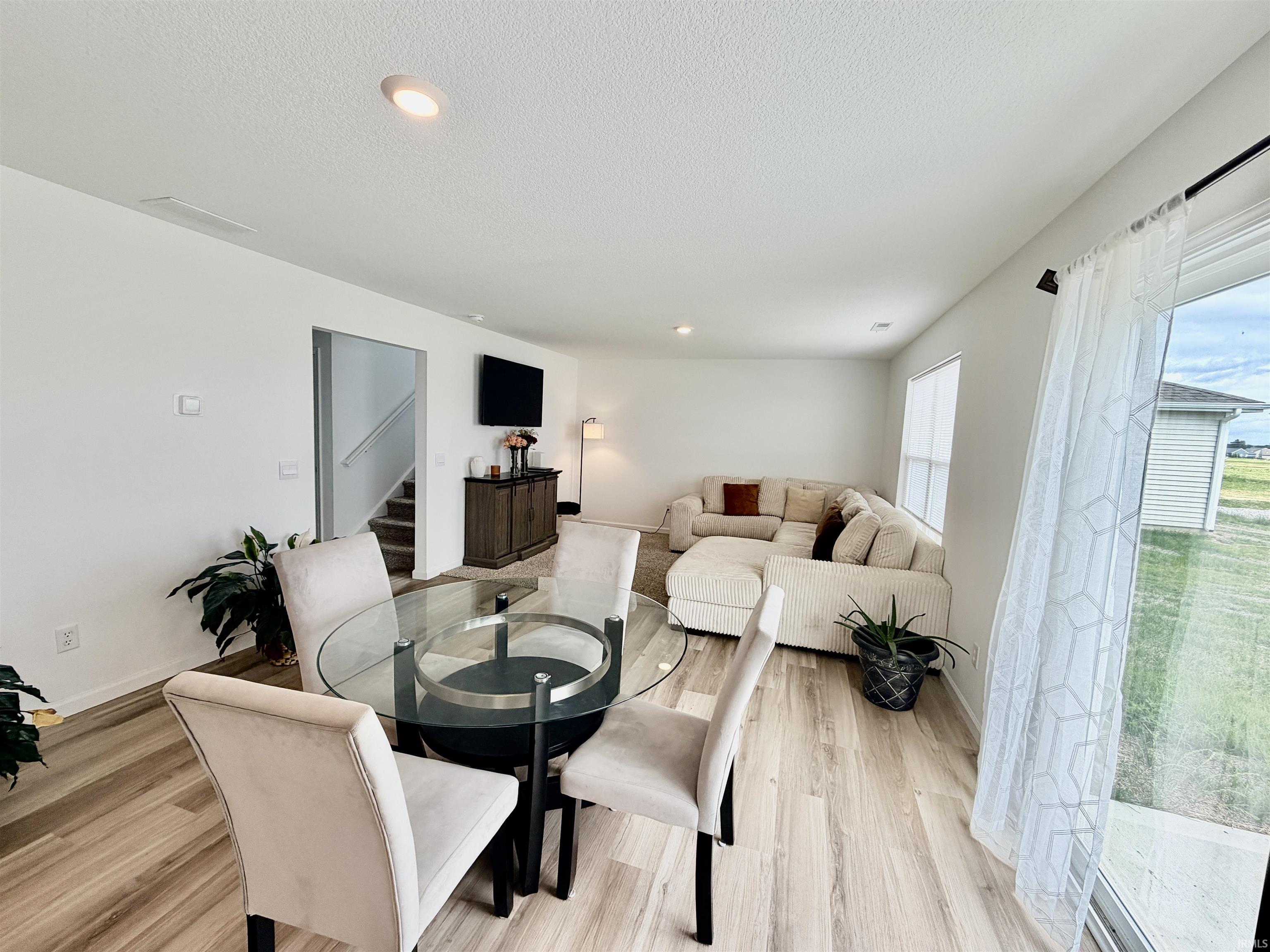 Open-concept living space featuring light wood-finish flooring, recessed lighting, and white walls