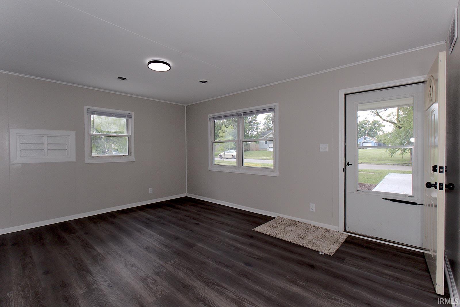 Entry space featuring dark wood-finish flooring, light grey walls, and a white entry door with a glass panel