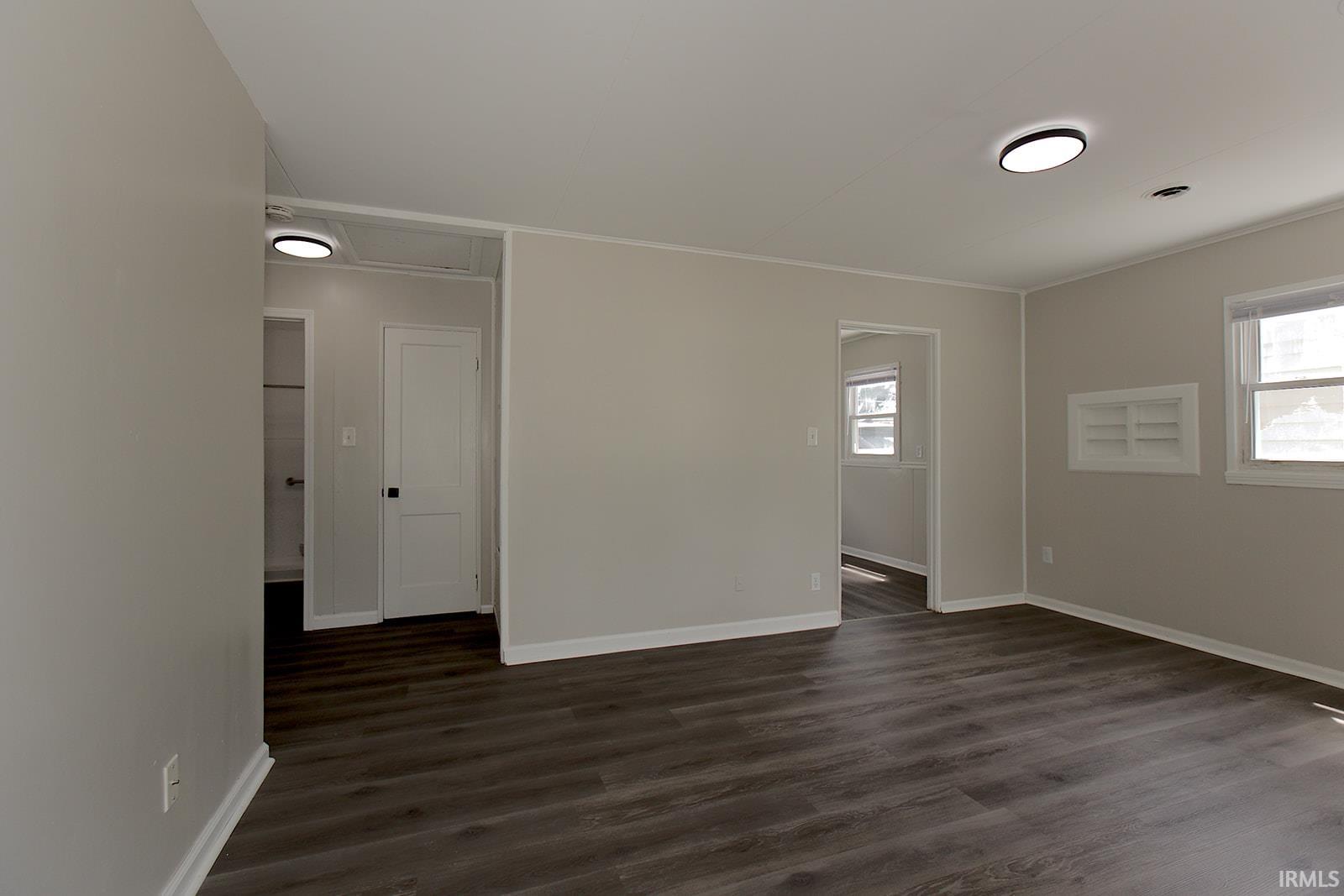 Spacious room featuring wood-finish flooring, light gray wall paint, and white trim
