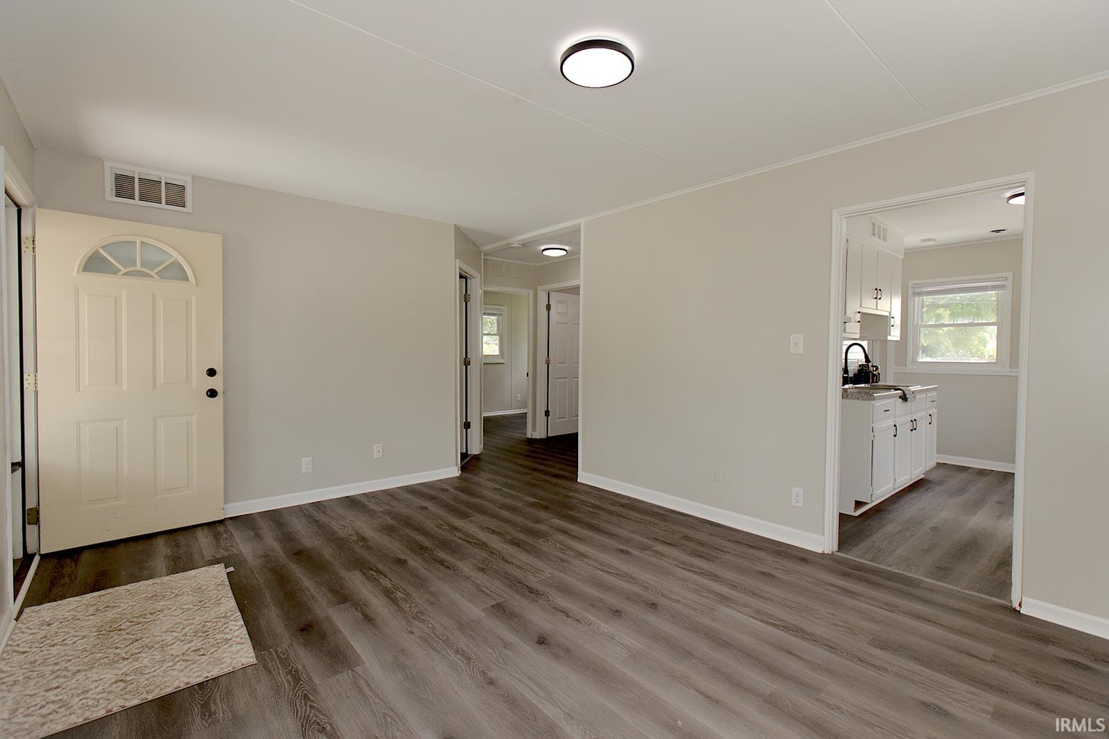 Spacious interior featuring wood-finish flooring, light grey wall paint, and recessed lighting fixtures