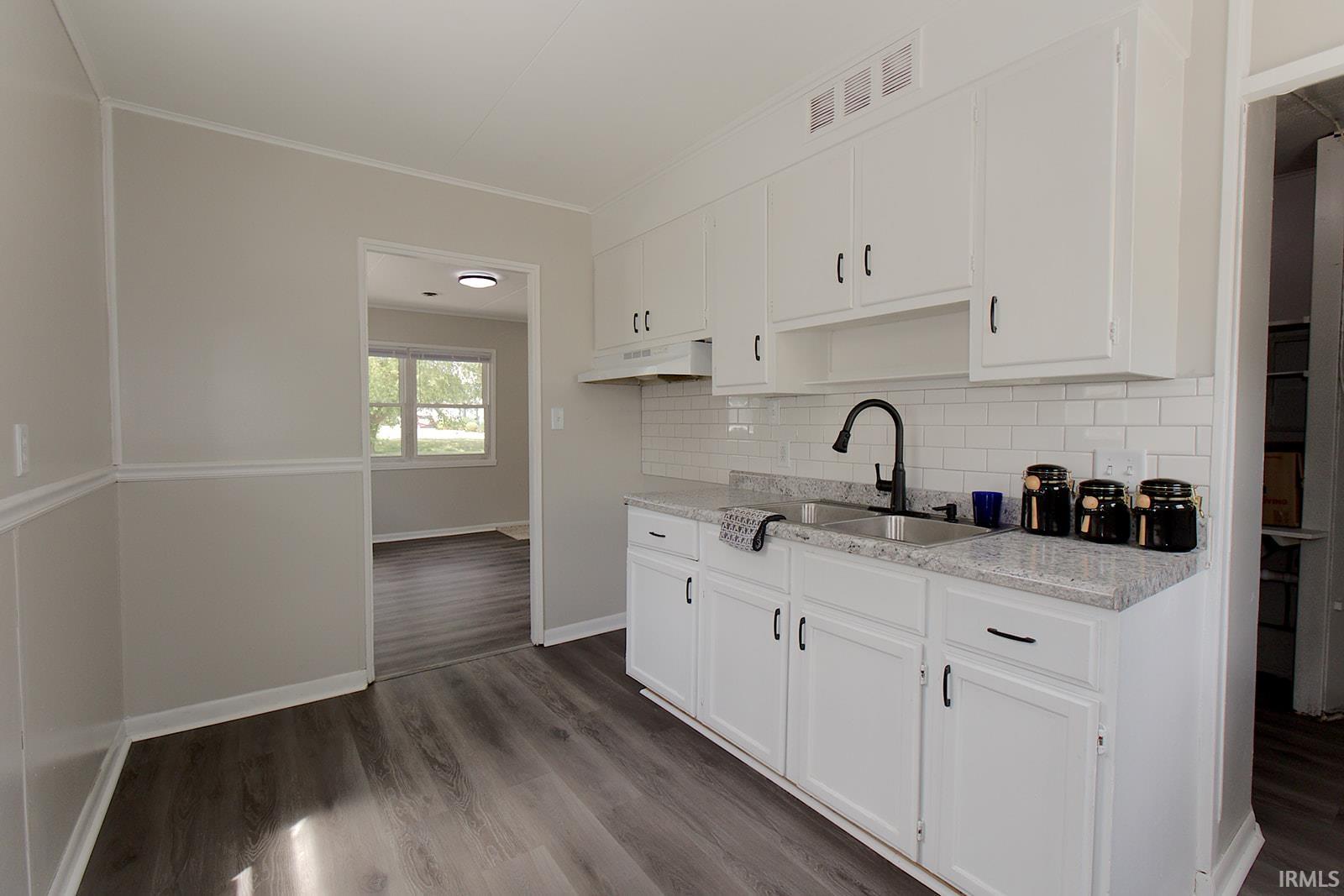 Kitchen featuring white cabinetry, a single basin stainless steel sink with a matte black faucet, granite-finish countertops, and a white subway tile backsplash