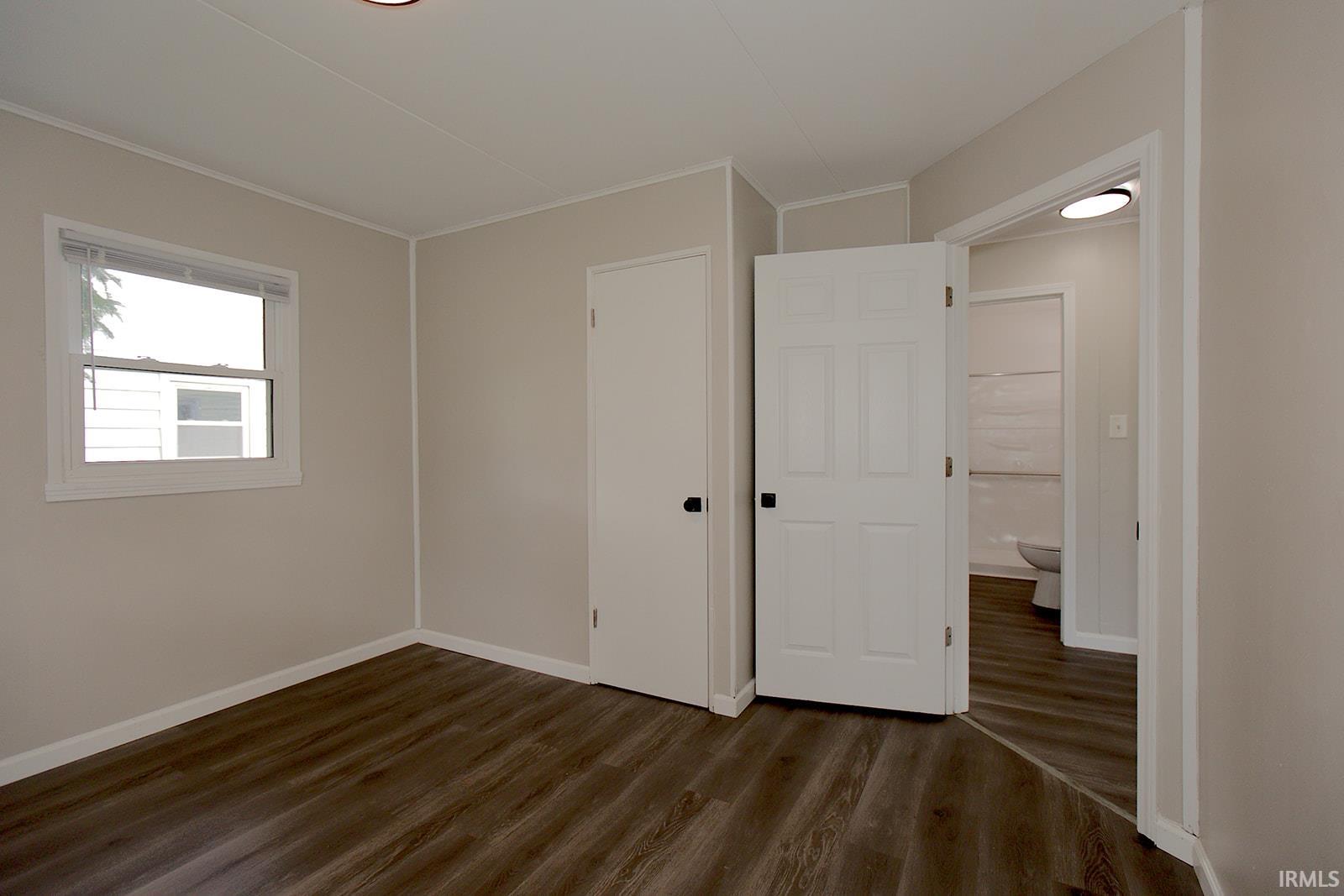 Room featuring wood-finish flooring, neutral wall tones, a recessed ceiling light, and a window with blinds