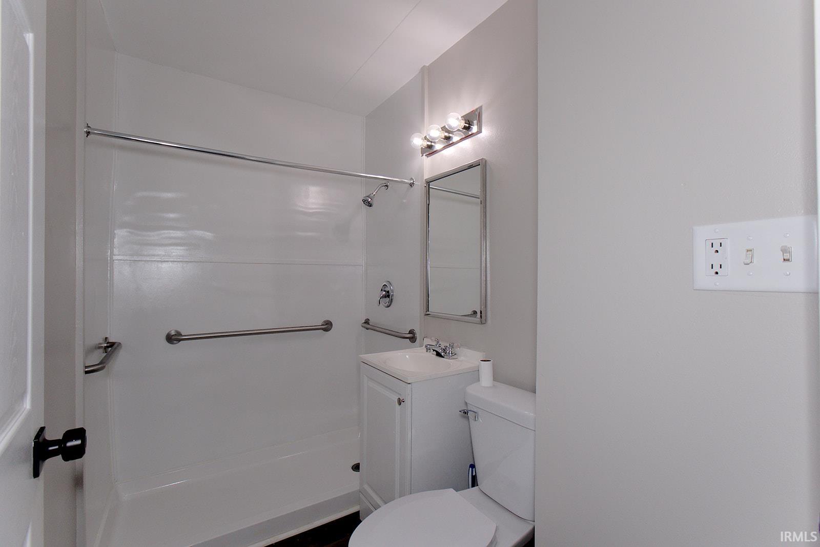 Bathroom featuring a white shower surround, chrome fixtures, a vanity with a white countertop and basin, and a mirrored medicine cabinet