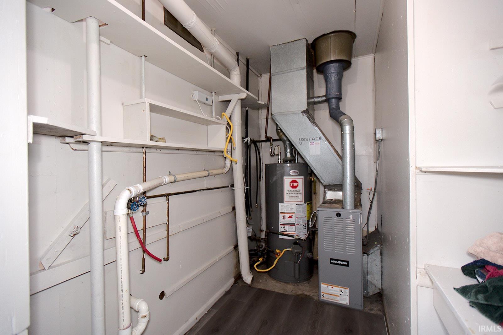 Utility area featuring a water heater, furnace, and various piping