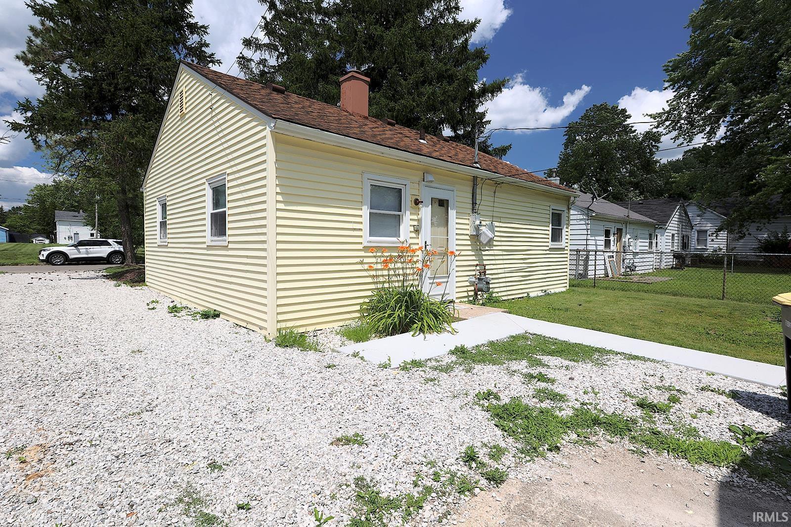 Yellow siding exterior with white trim windows and a brown shingle roof