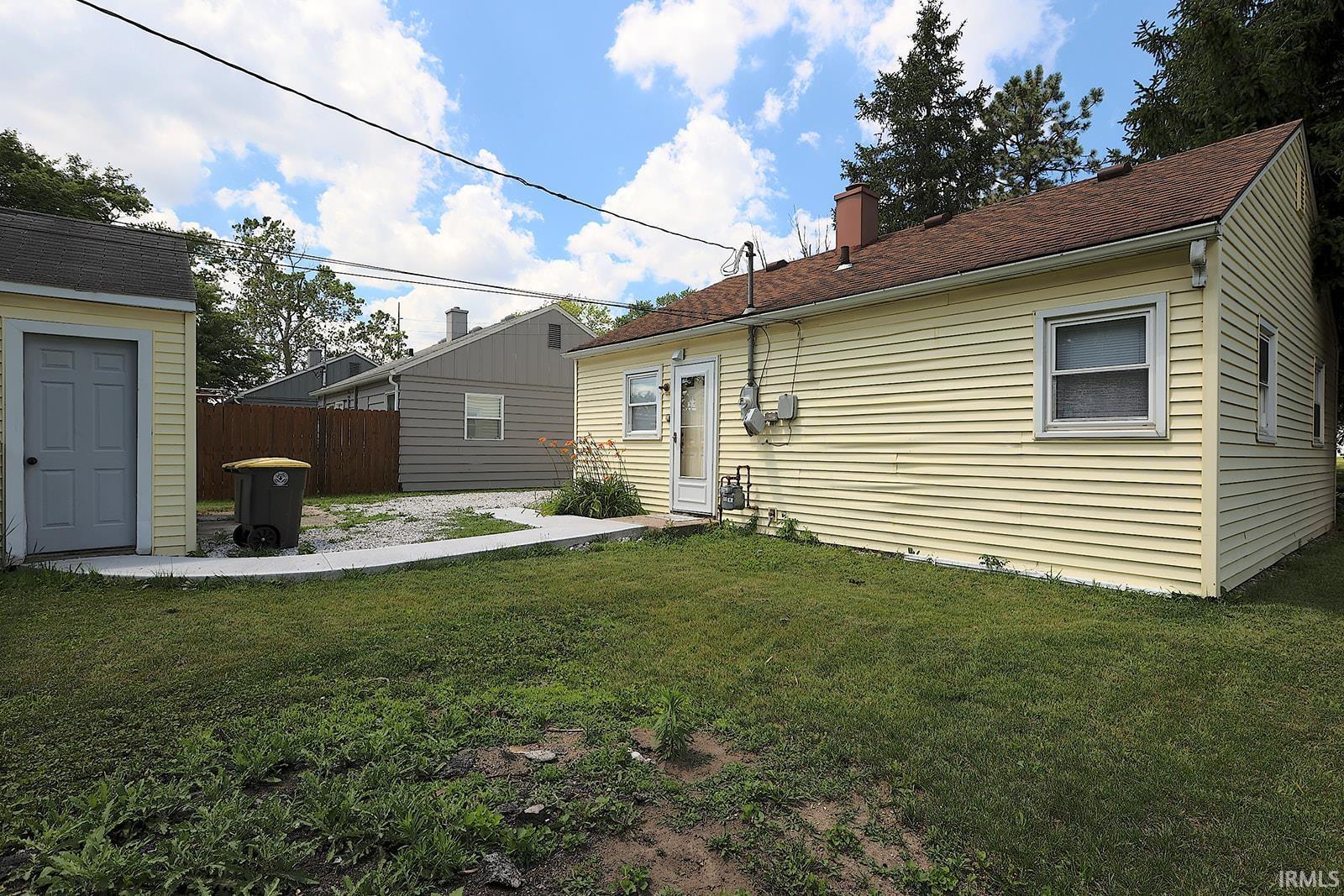 Rear exterior featuring yellow siding and a brown shingle roof
