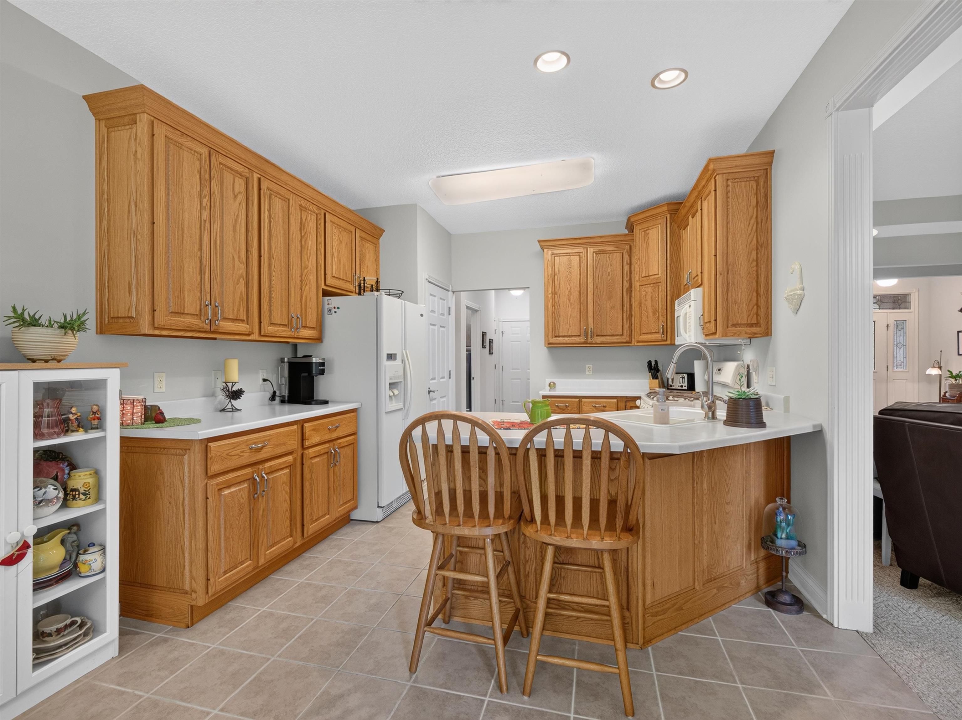 Kitchen featuring wood cabinetry, white countertops, a central island with bar seating, and tile flooring