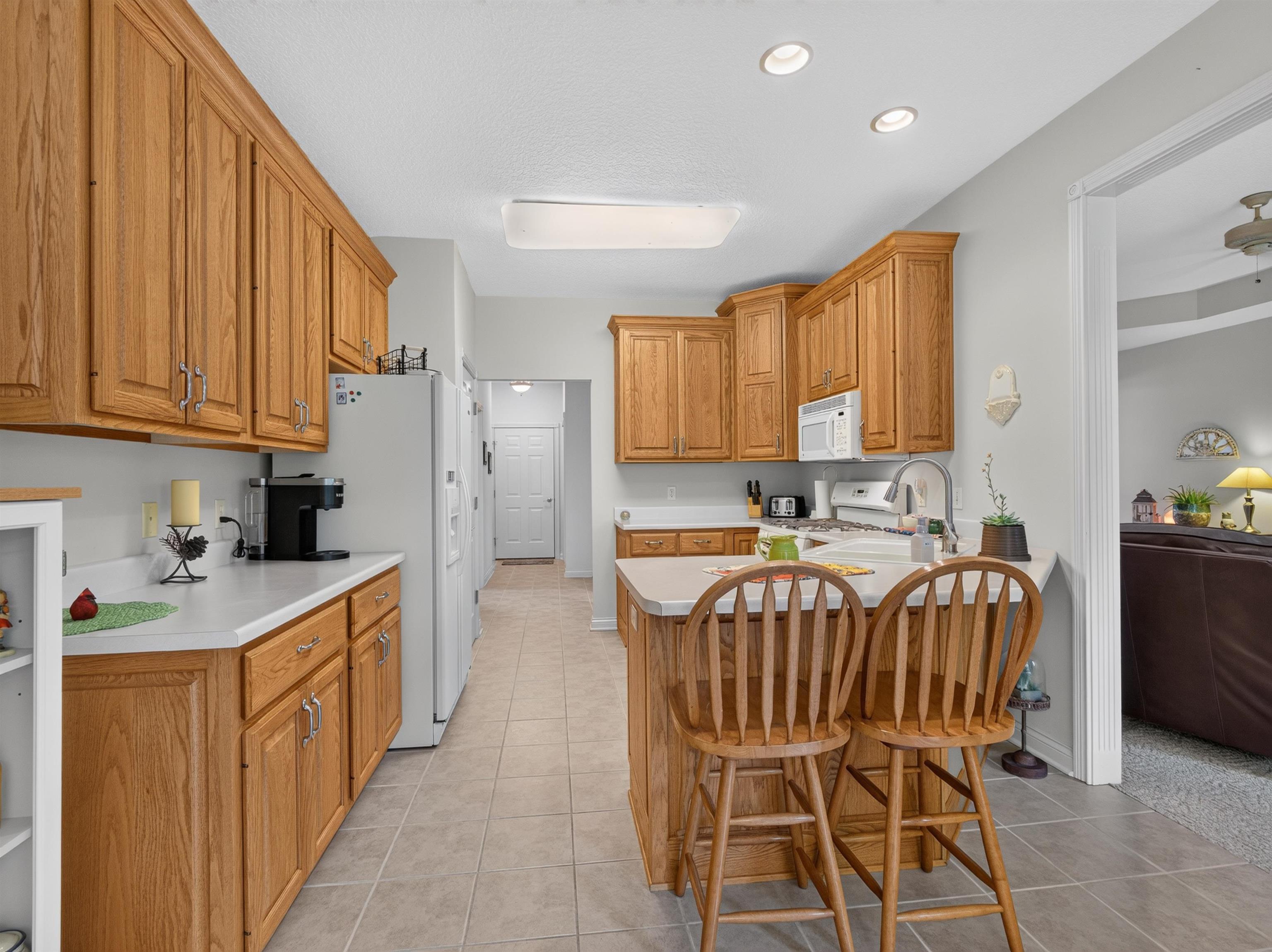 Kitchen featuring wood cabinetry, white countertops, a built-in microwave, and an island with seating