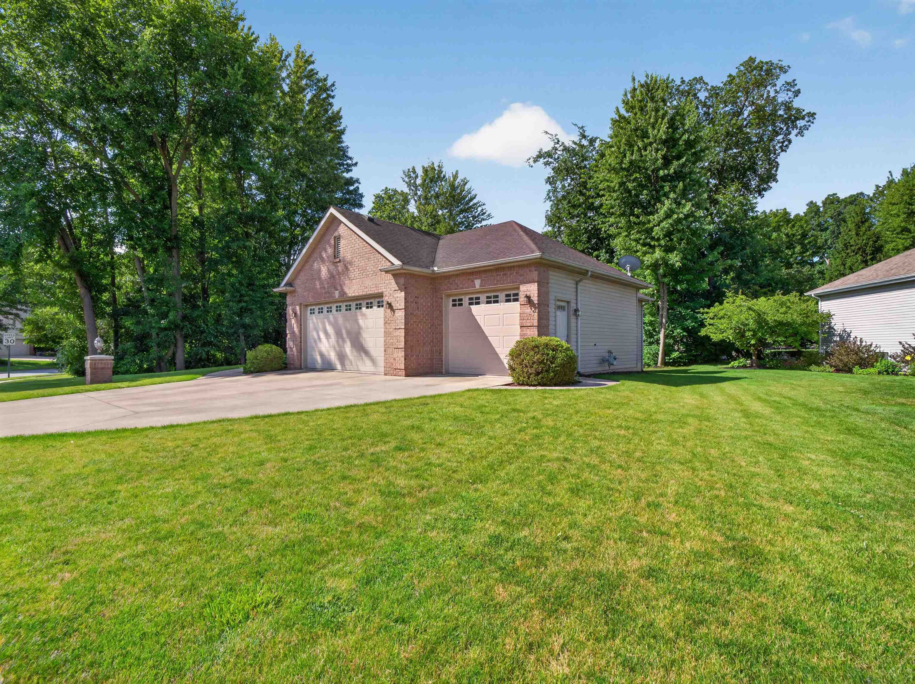 Brick-clad garage structure featuring two overhead doors and a concrete driveway
