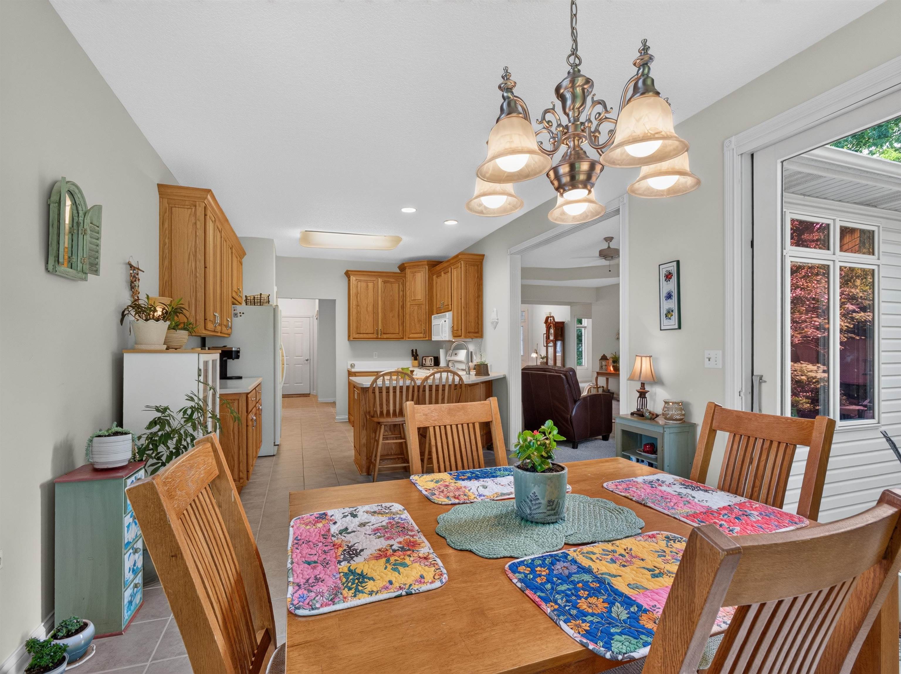 Dining area featuring a classic chandelier, wood-finish dining table, and access to a kitchen with wood cabinetry