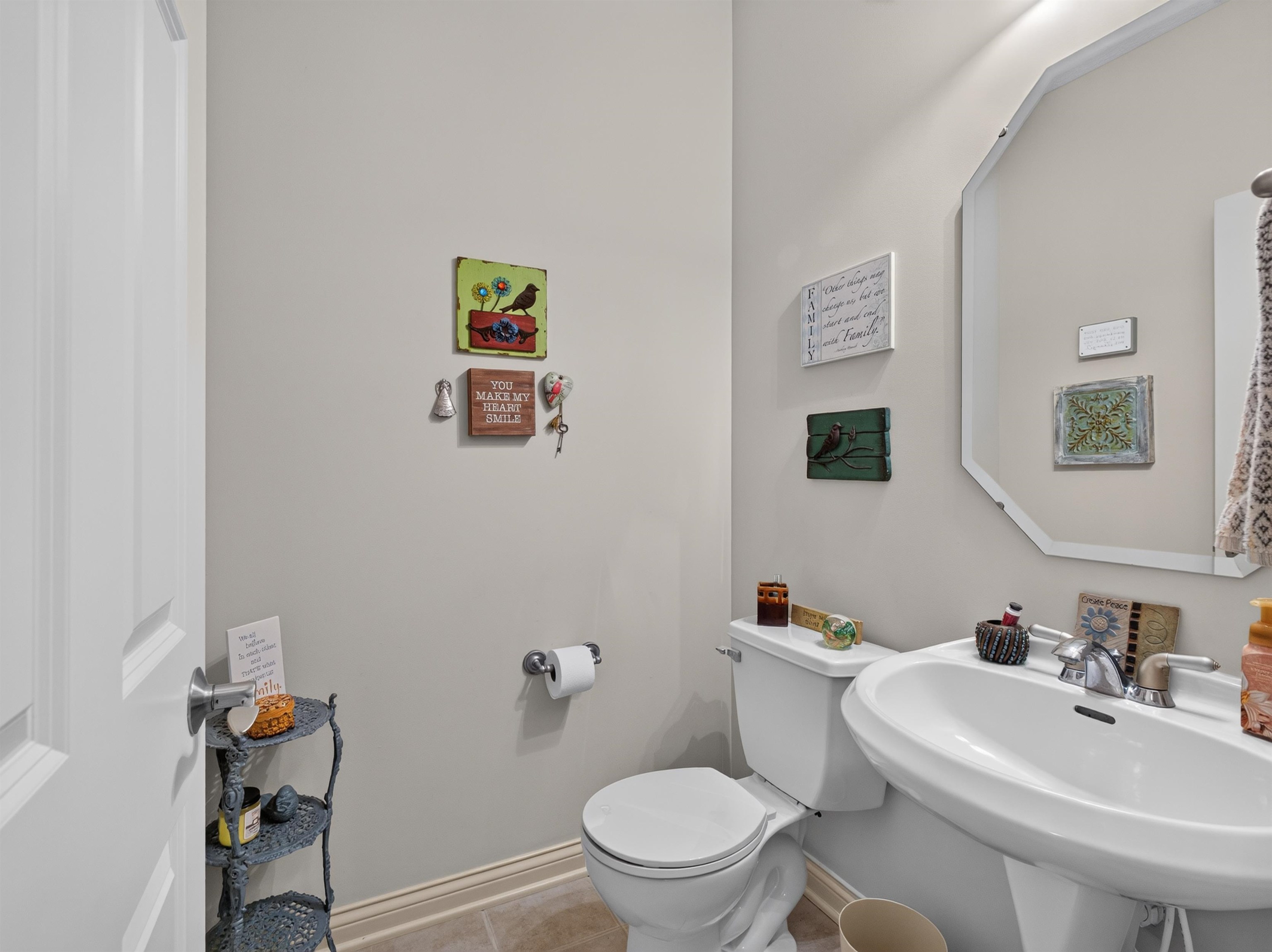 Pedestal sink with chrome fixtures, an octagonal mirror, and a white toilet