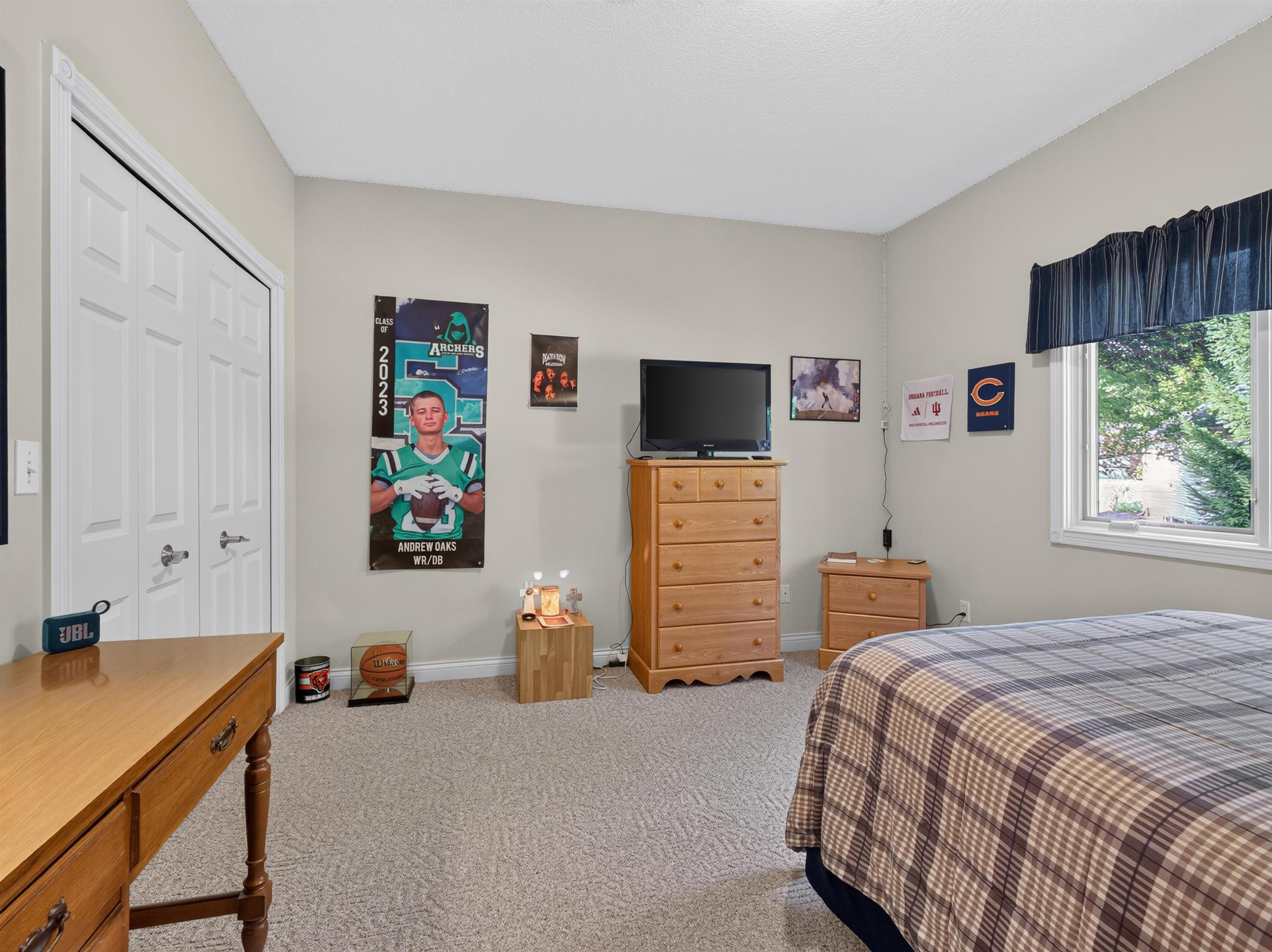 Neutral wall color, light-toned carpet flooring, white bi-fold closet doors, and a window with exterior views
