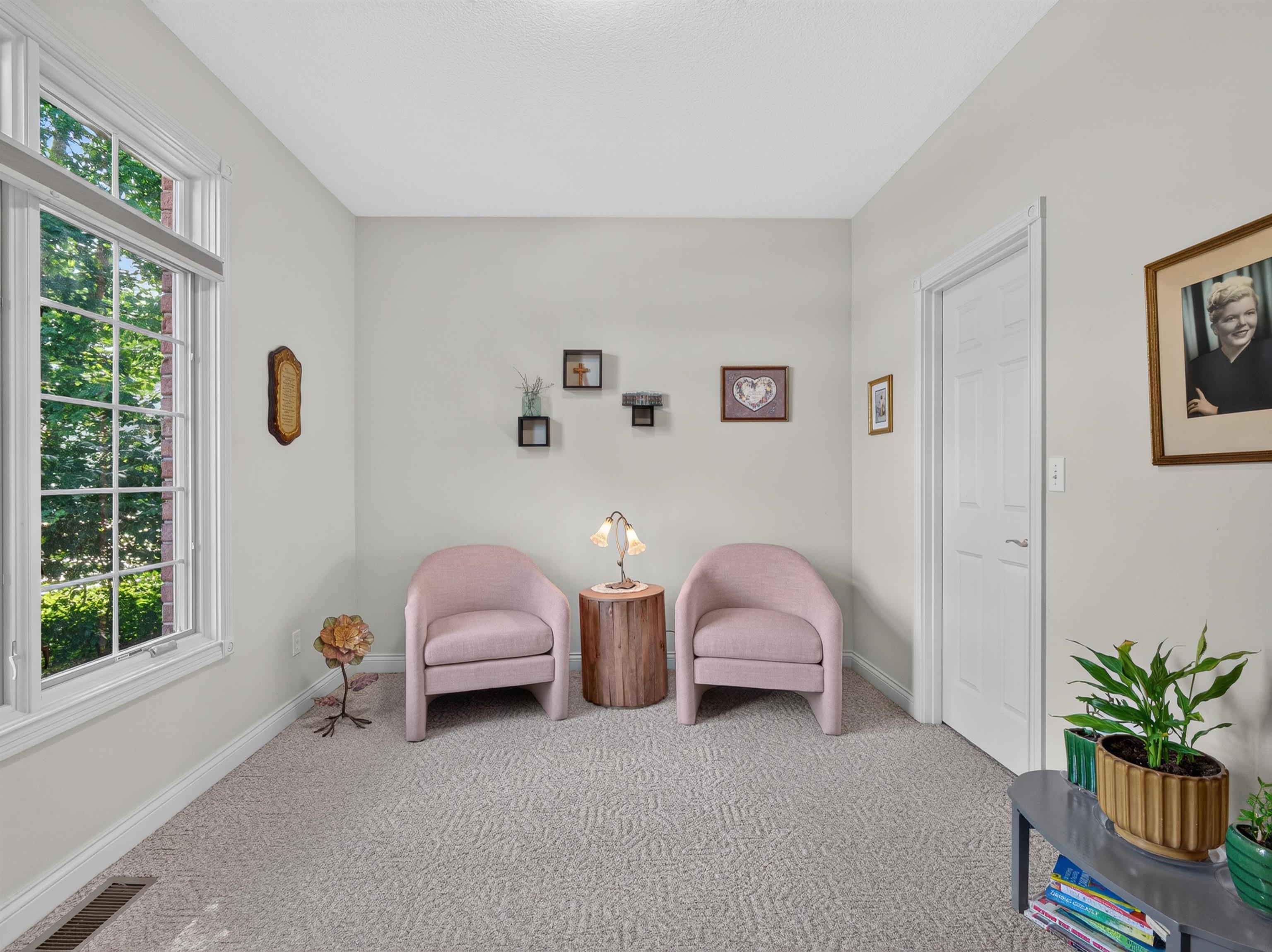 Room featuring a large multi-pane window, light-colored walls, patterned carpeting, white baseboards, and a white interior door