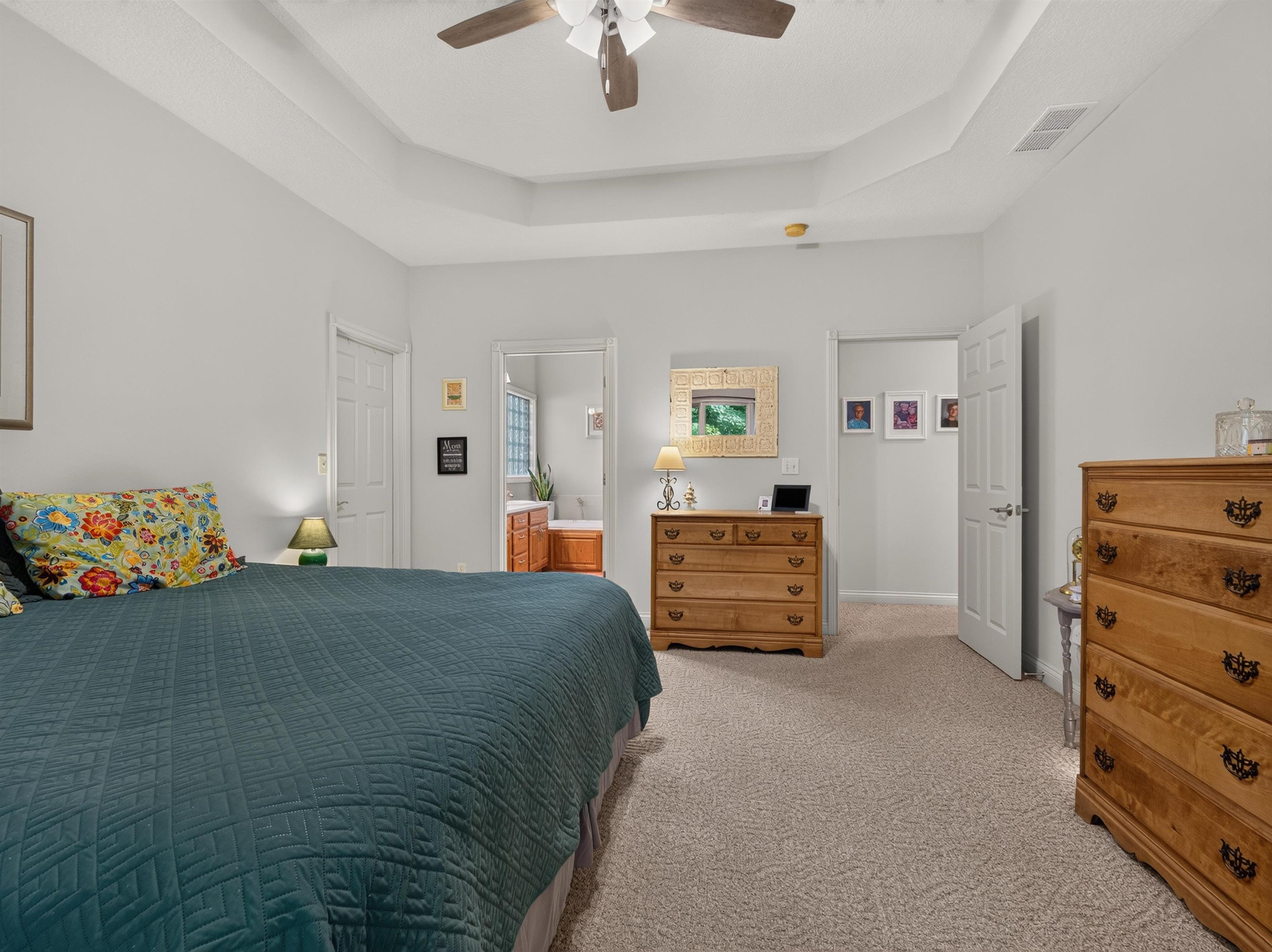 Carpeted room featuring a ceiling fan, tray ceiling, and light-colored walls