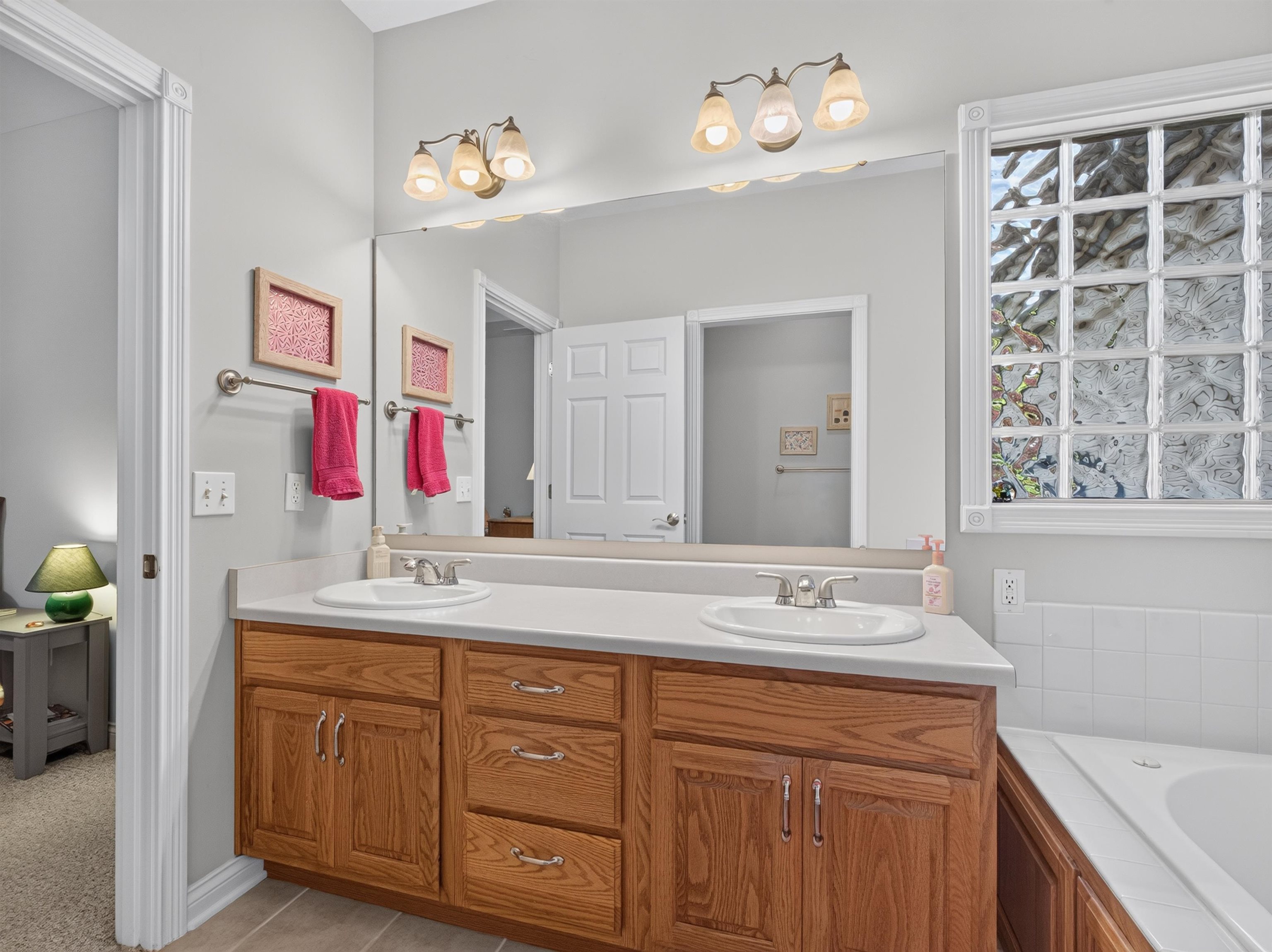Bathroom vanity with dual sinks, wood cabinetry, and a light-toned countertop