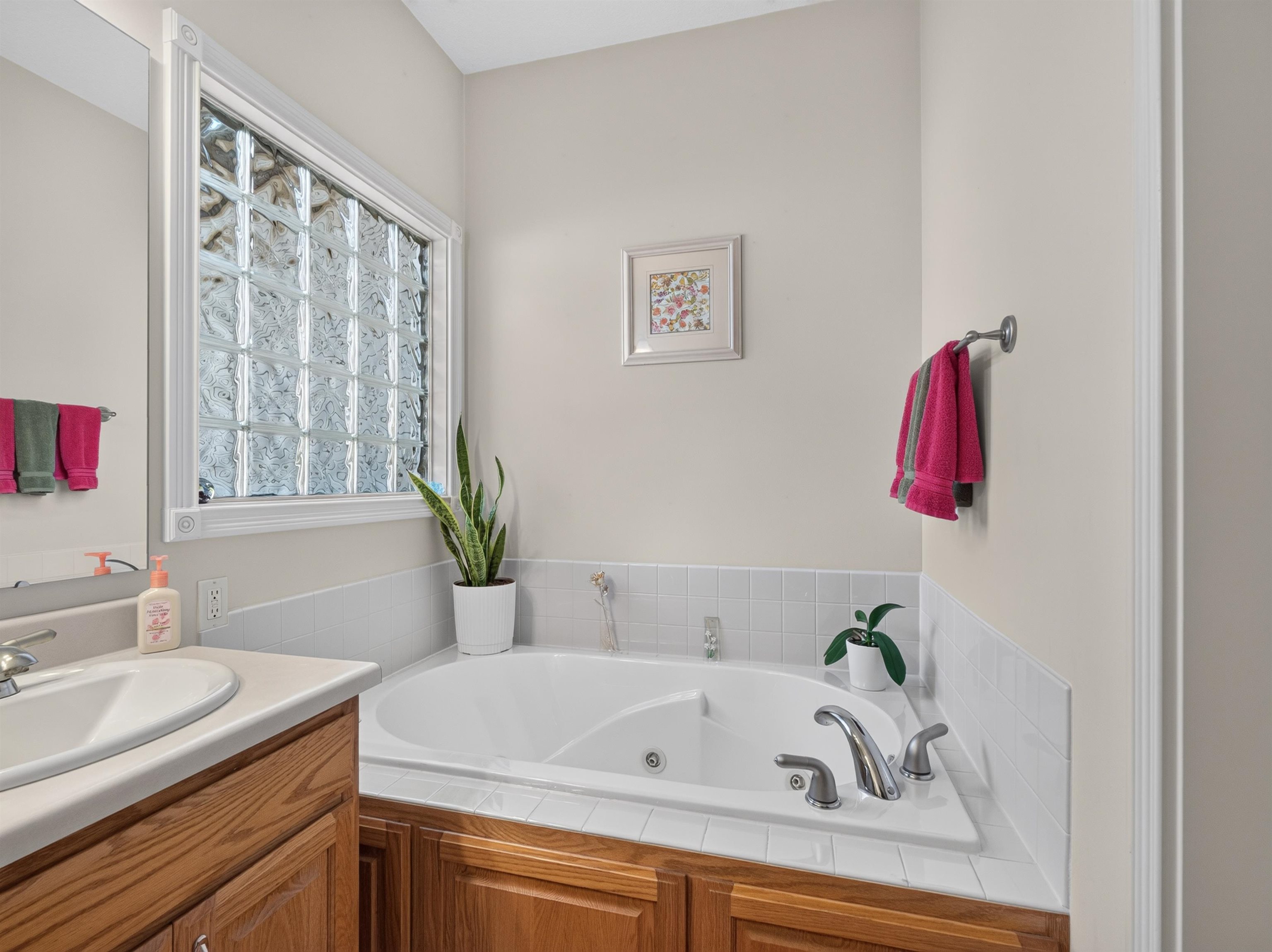 Soaking tub with white tile surround and a privacy glass block window