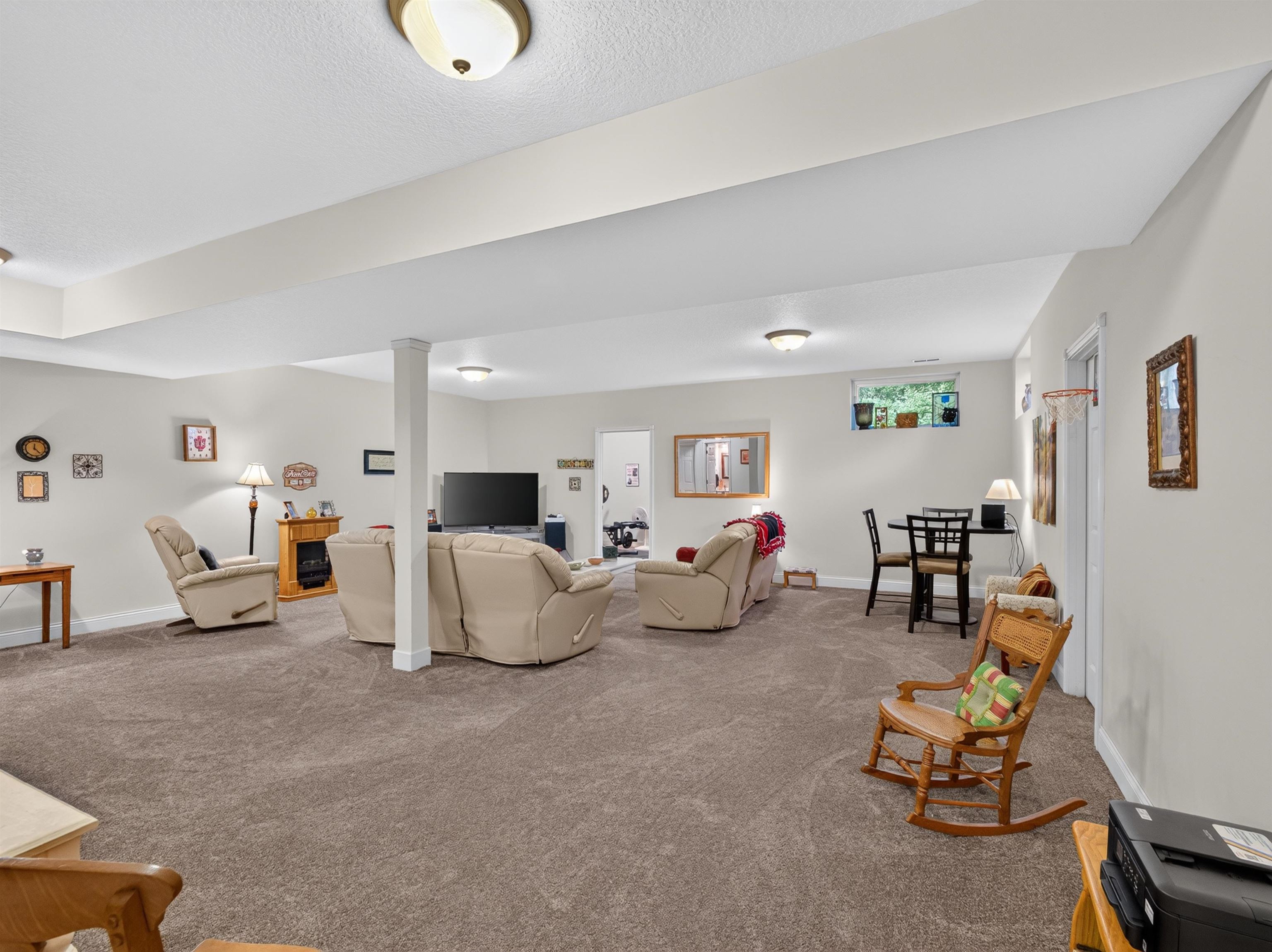 Spacious room featuring neutral carpeting, recessed lighting, white walls, and a visible window for natural light