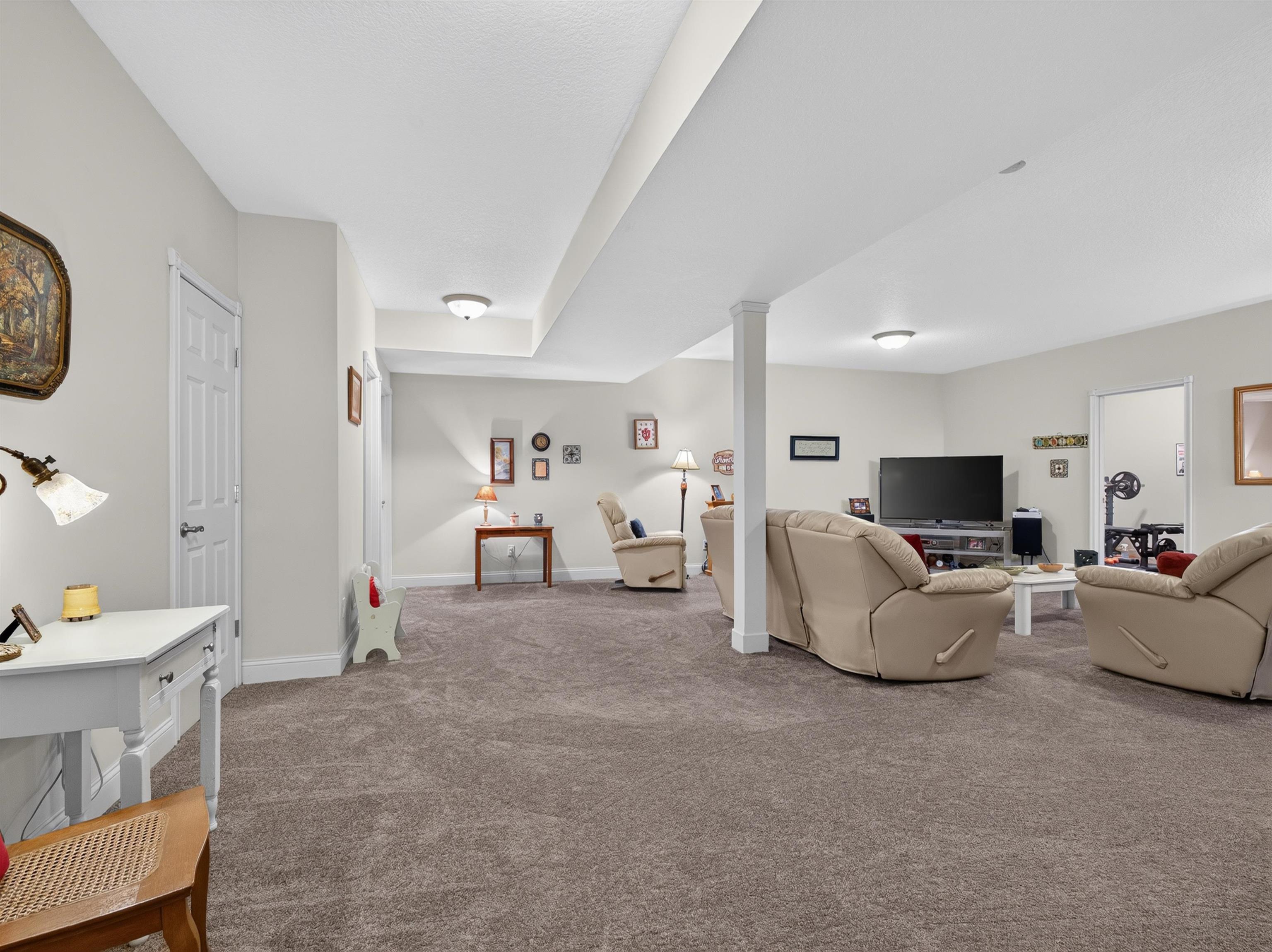 Spacious room featuring neutral carpeting, light-toned walls, recessed lighting, a structural column, and a white six-panel door