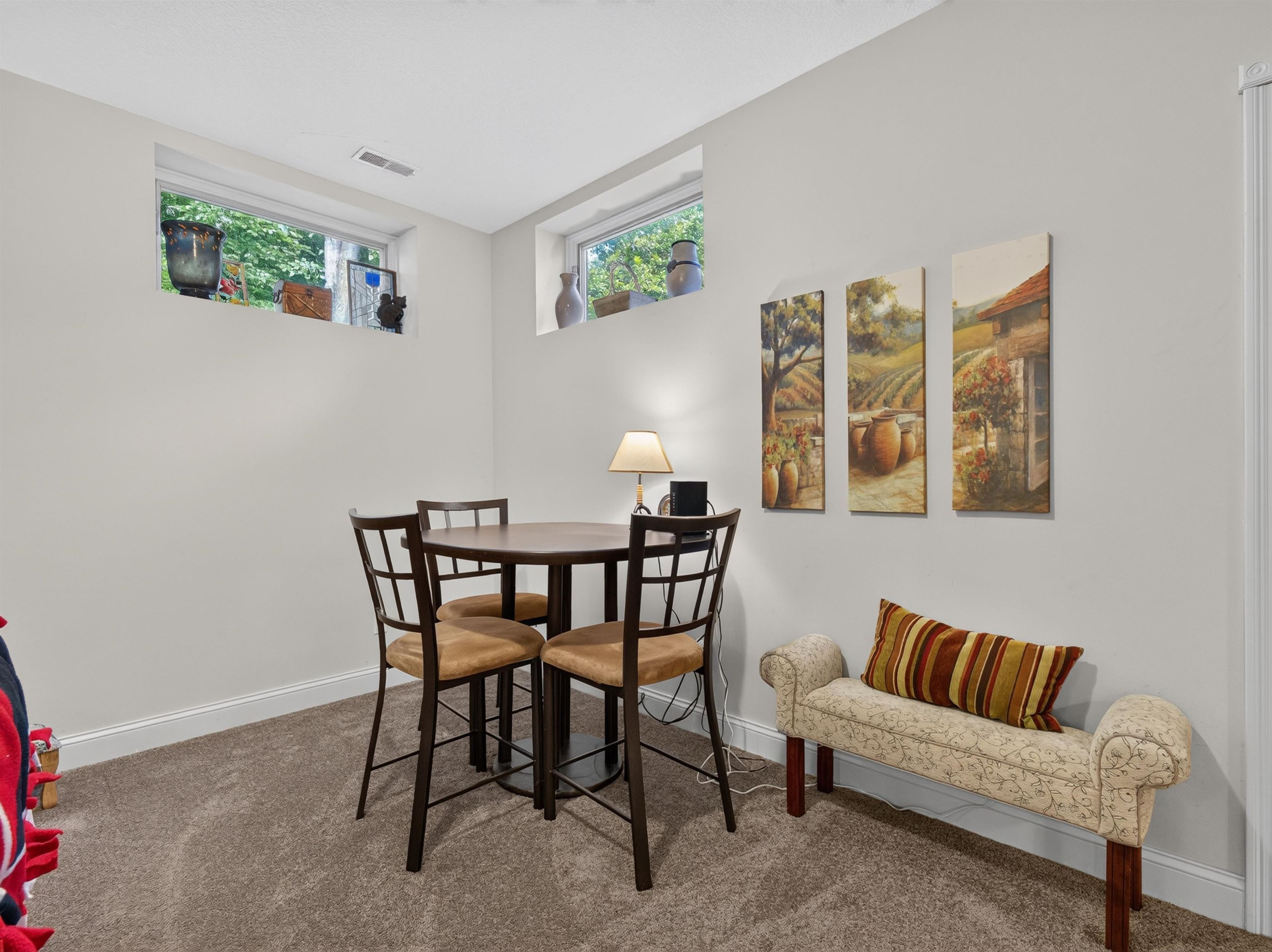 Carpeted room featuring two egress windows, white baseboards, and neutral wall paint