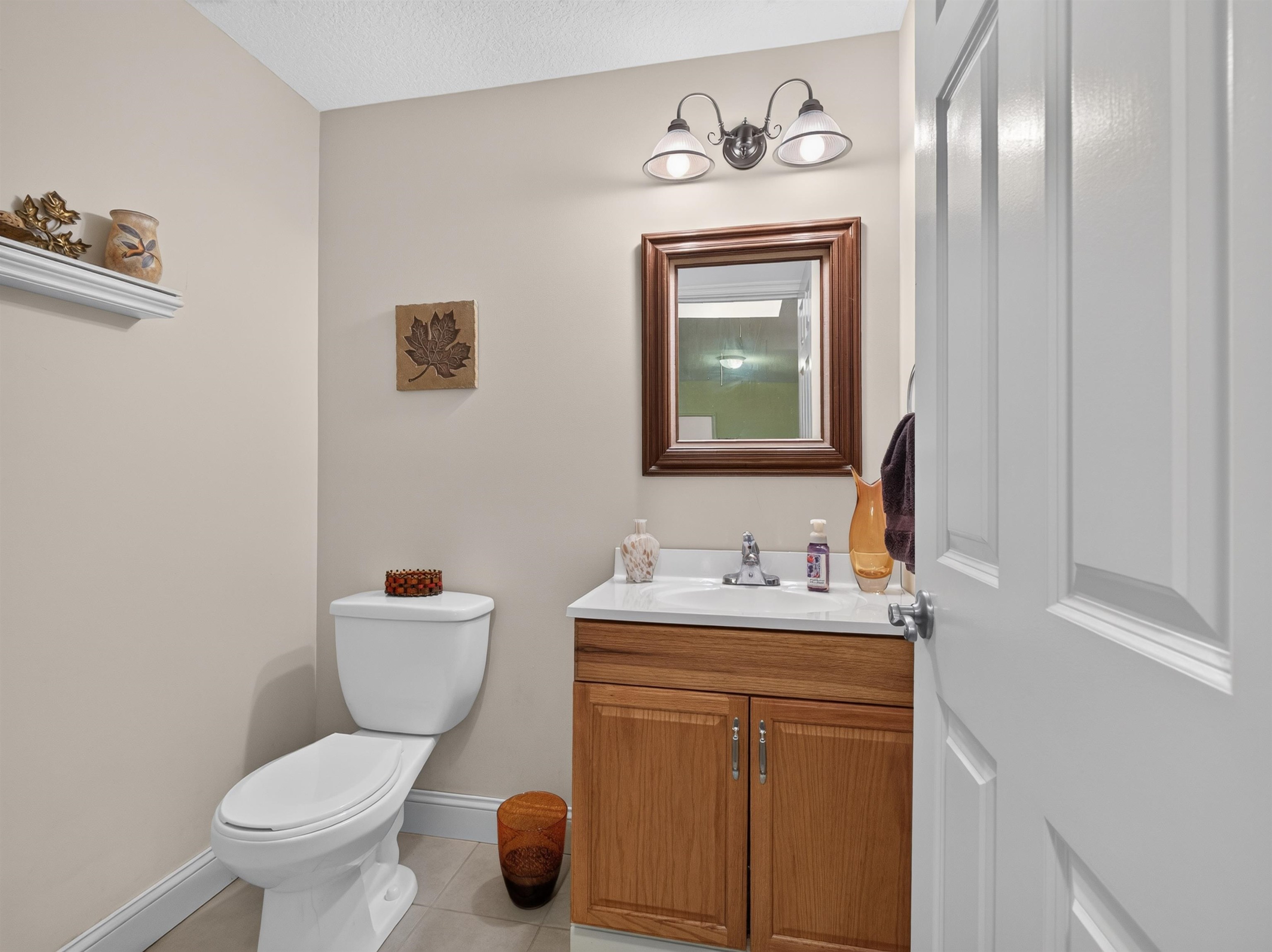 Bathroom featuring a wood vanity with a white countertop, a rectangular mirror with a wood frame, and a two-light fixture