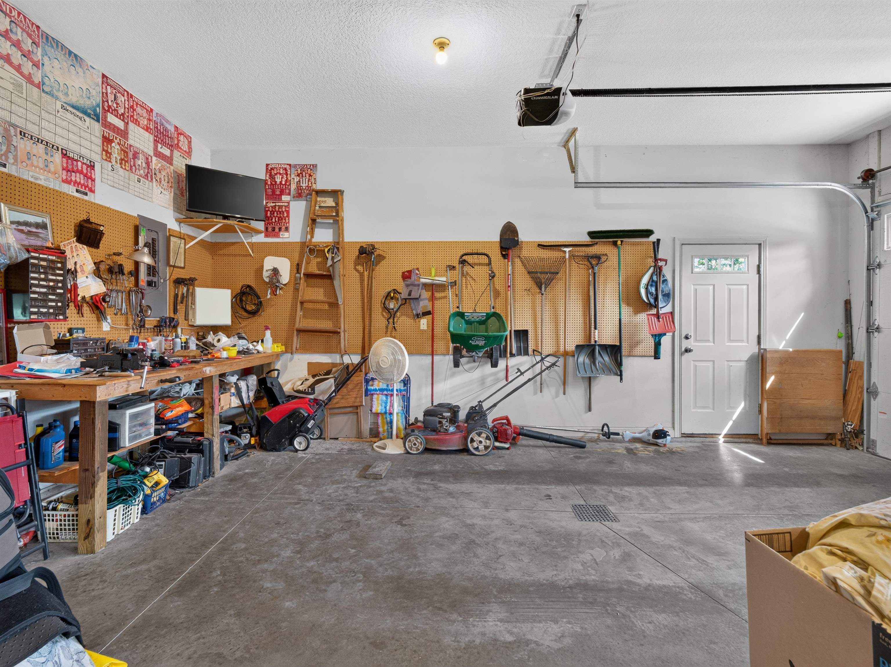 Concrete floor garage featuring a workshop area with pegboard organization, an interior access door, and an automatic garage door opener